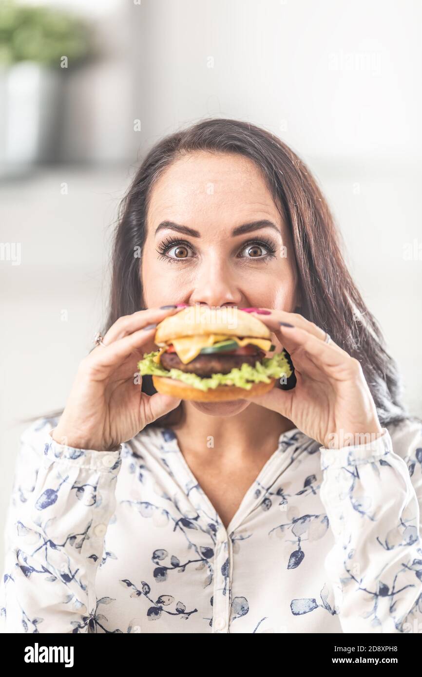 Junge Frau hält einen Burger vor ihrem Mund. Stockfoto