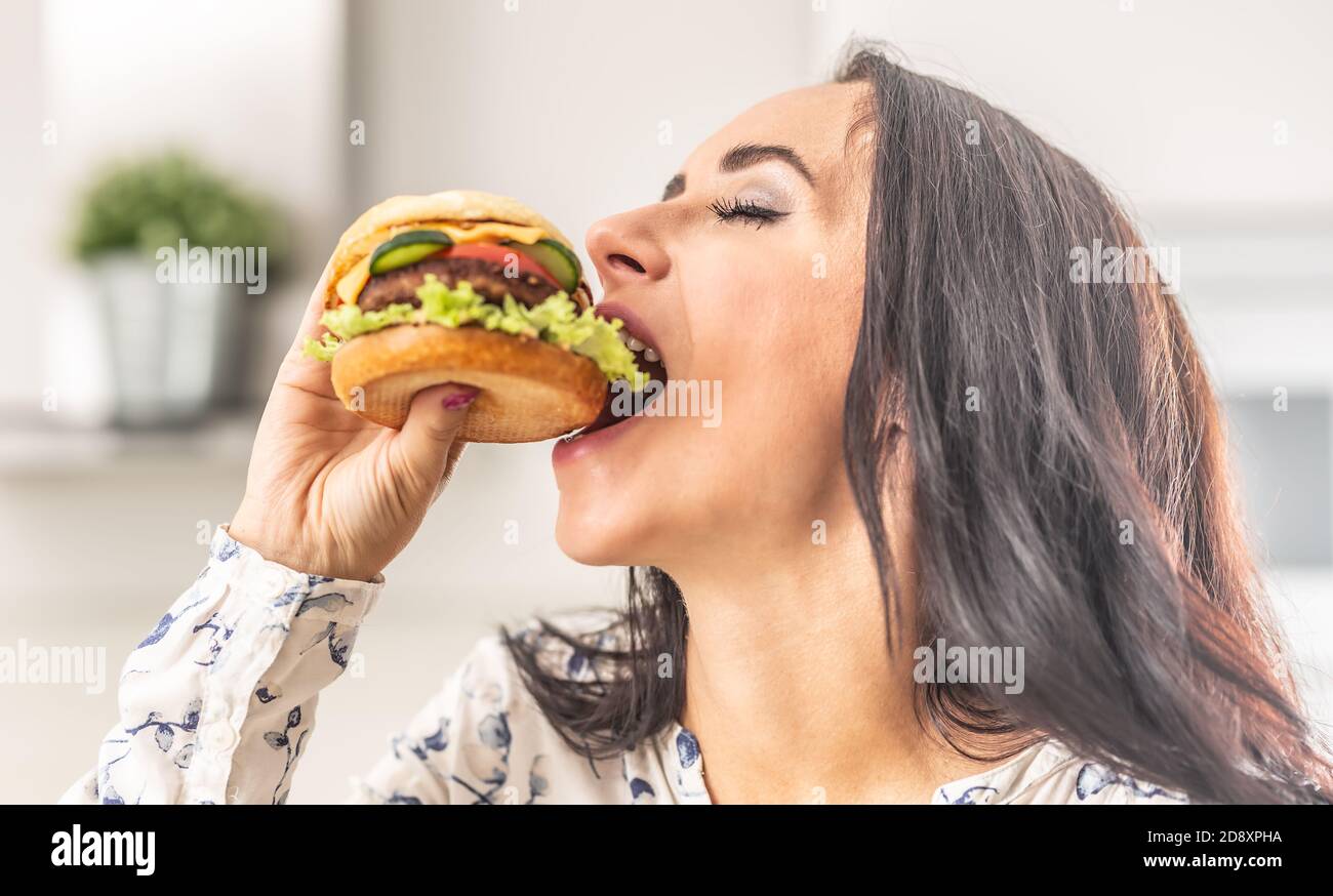 Frau nimmt einen großen Bissen von einem dicken Hamburger. Stockfoto