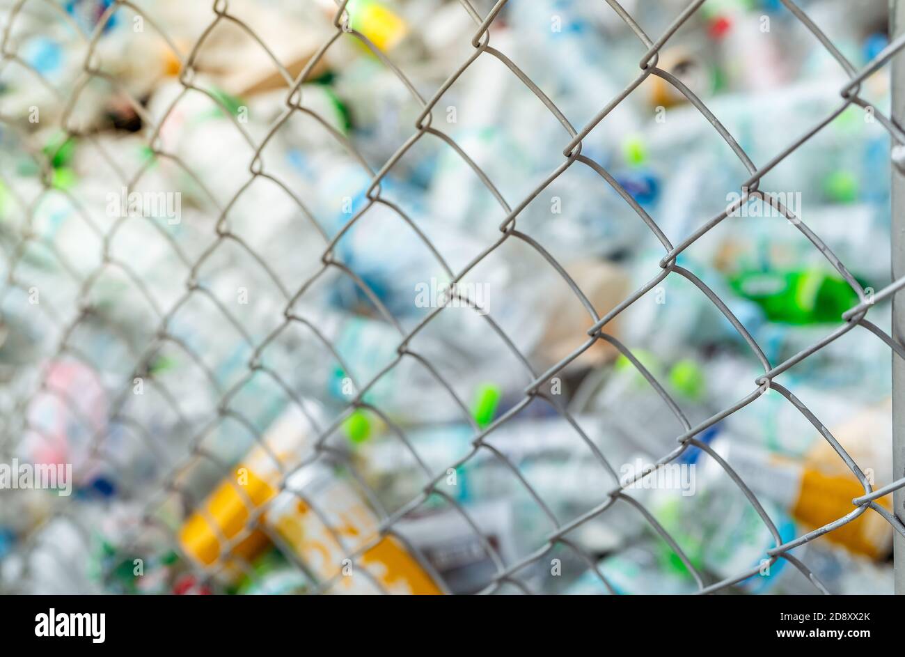 Verschwommenes Foto von Stapel von leerem Wasser Plastikflasche im Gitter Zaun Papierkorb. Plastikflaschen Abfälle für Recycling im Recycling-Geschäft. Kunststoffabfall. Stockfoto