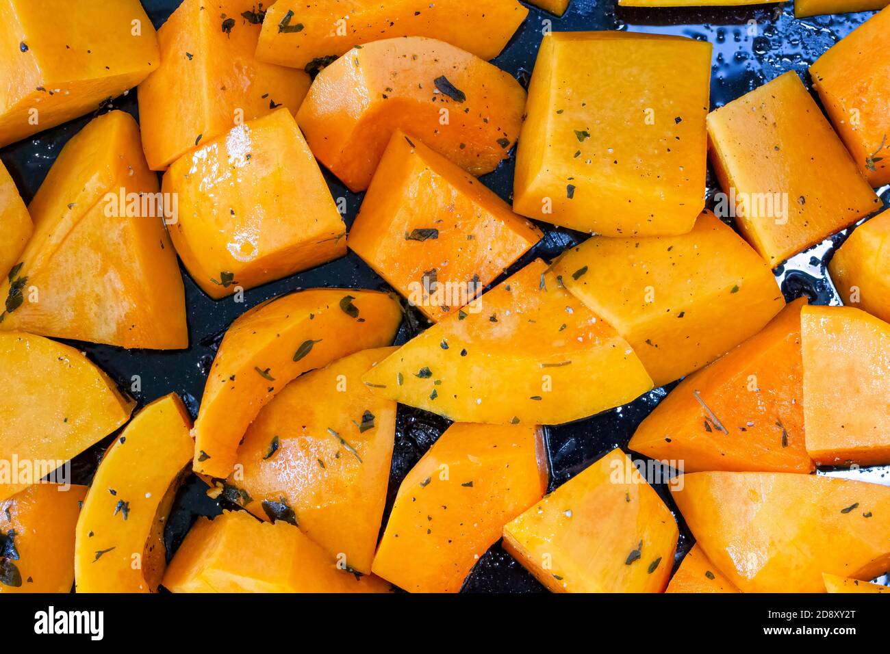 Nahaufnahme von Butternut-Kürbisstückchen, die zum Braten vorbereitet wurden, auf einem Backblech Stockfoto