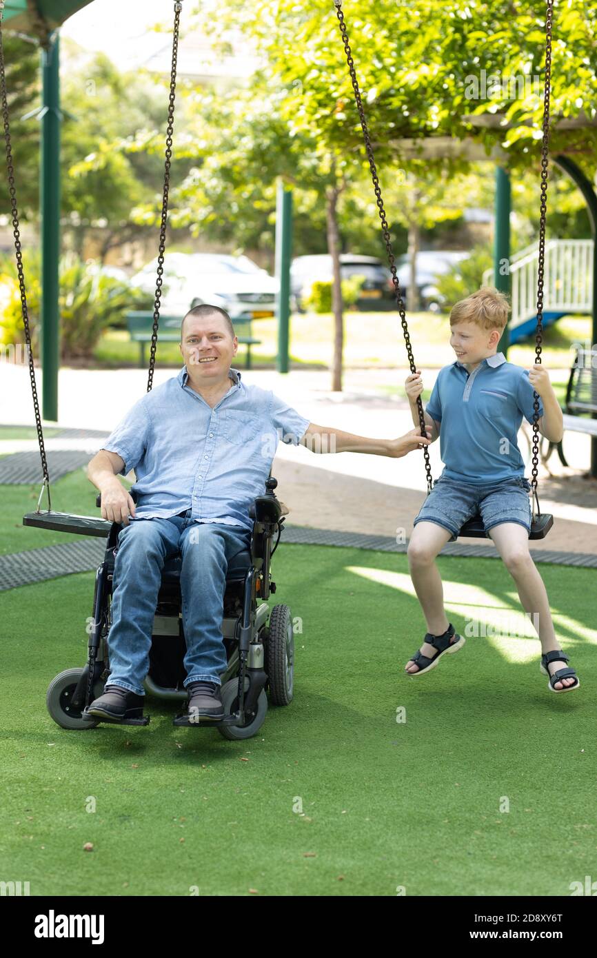 Behinderten Vater spielen mit seinem kleinen Sohn auf dem Spielplatz. Stockfoto