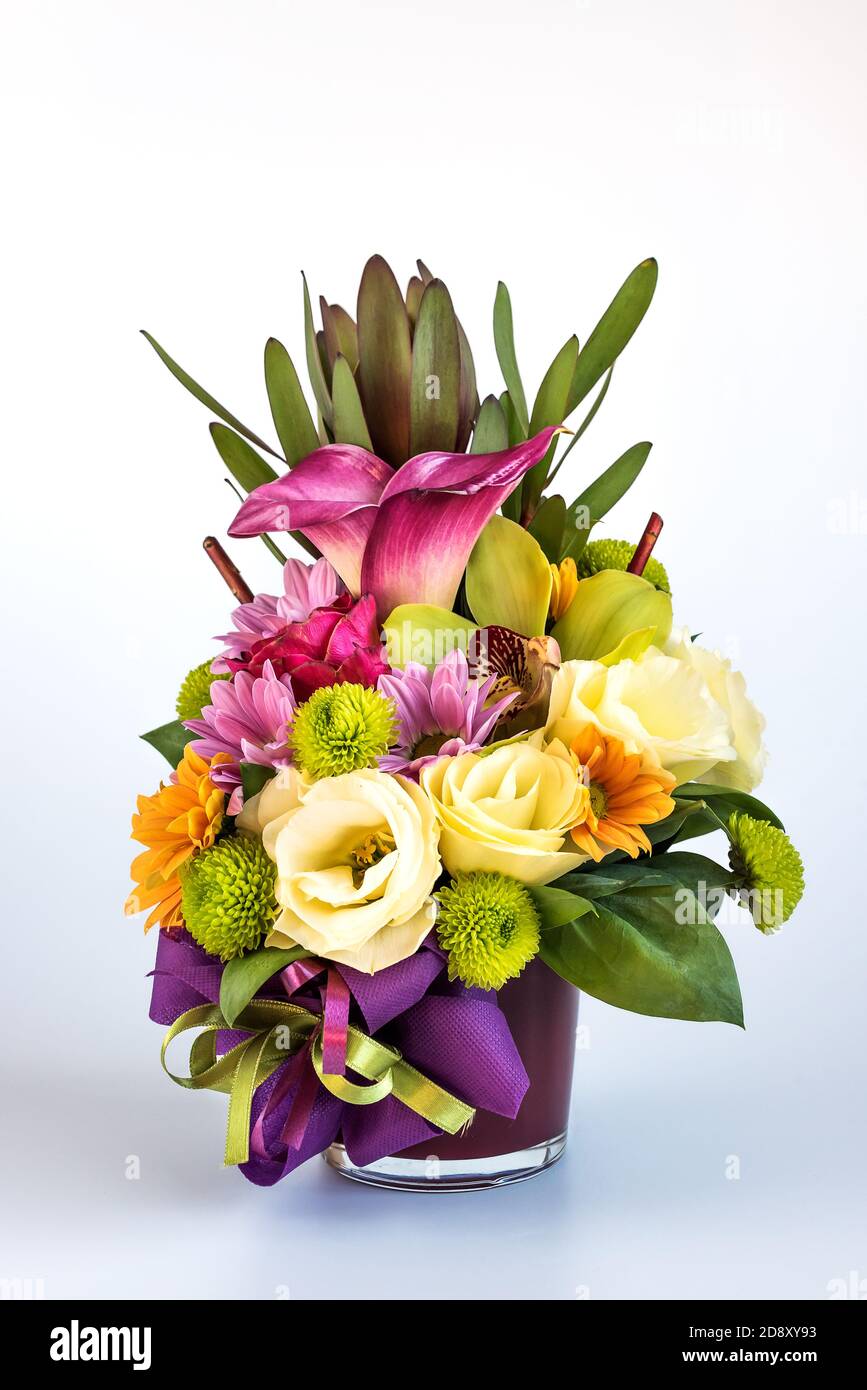 Blumenarrangement in einer lila Vase auf weißem Hintergrund. Stockfoto