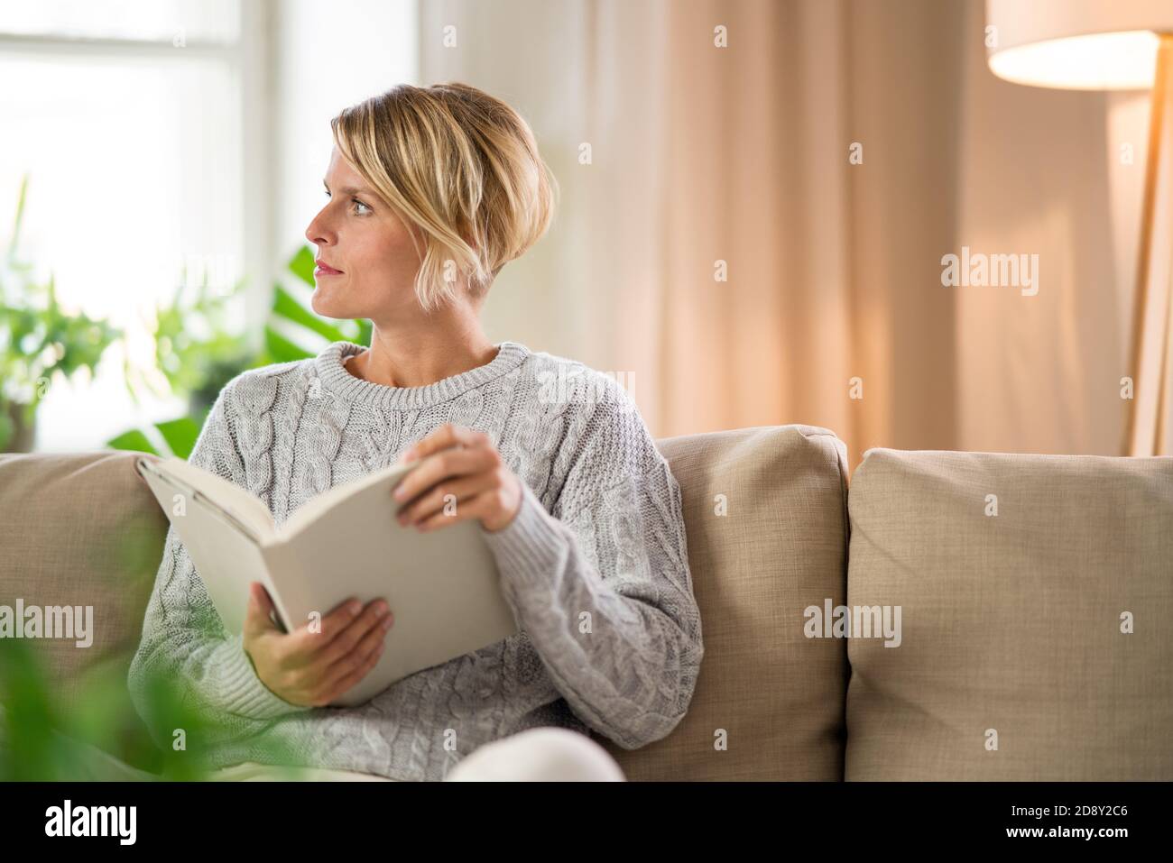 Portrait der Frau entspannend mit Buch drinnen zu Hause, psychische Gesundheit Konzept. Stockfoto