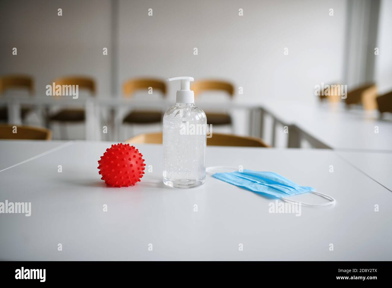 Abstraktes Modell von covid-19, antiseptisches Reinigungsgel und Gesichtsmaske auf dem Schreibtisch in der Schule, Coronavirus-Konzept. Stockfoto