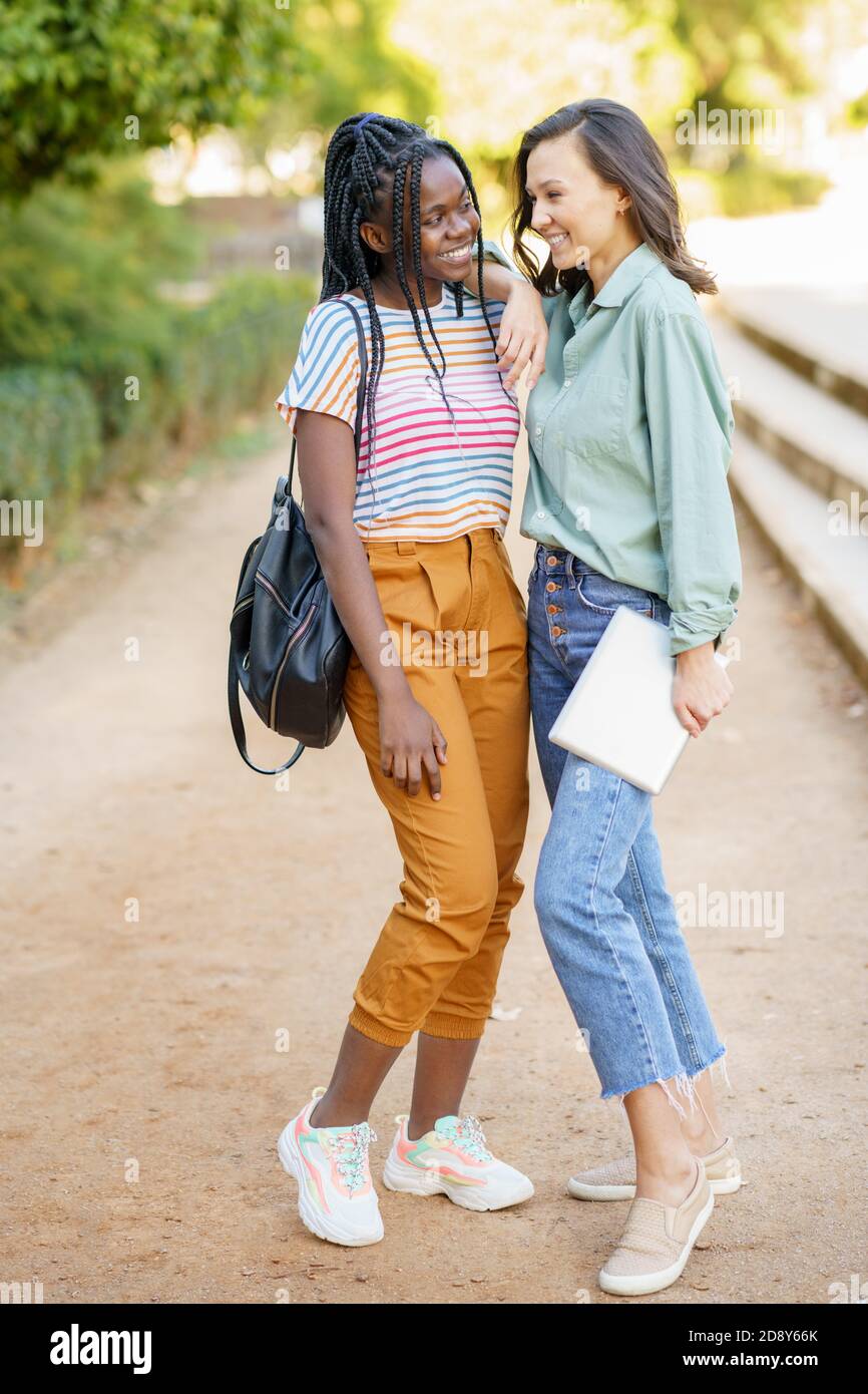 Zwei multiethnische Mädchen posieren zusammen mit farbenfroher Freizeitkleidung Stockfoto