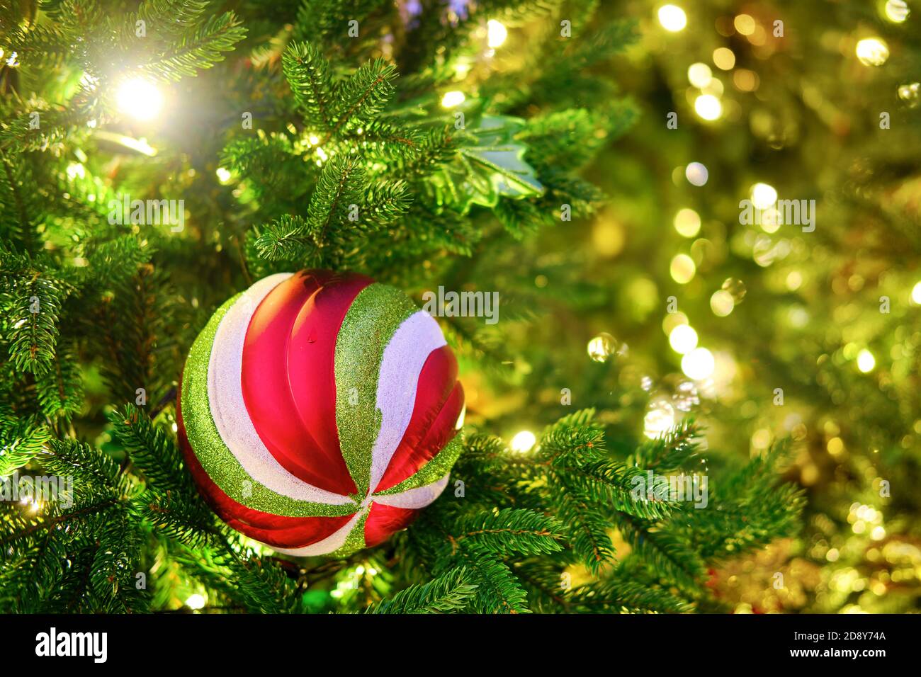 Verdrehte Kugeln auf dem Weihnachtsbaum und Bokeh Hintergrund Girlande Lichter, kopieren Raum Stockfoto
