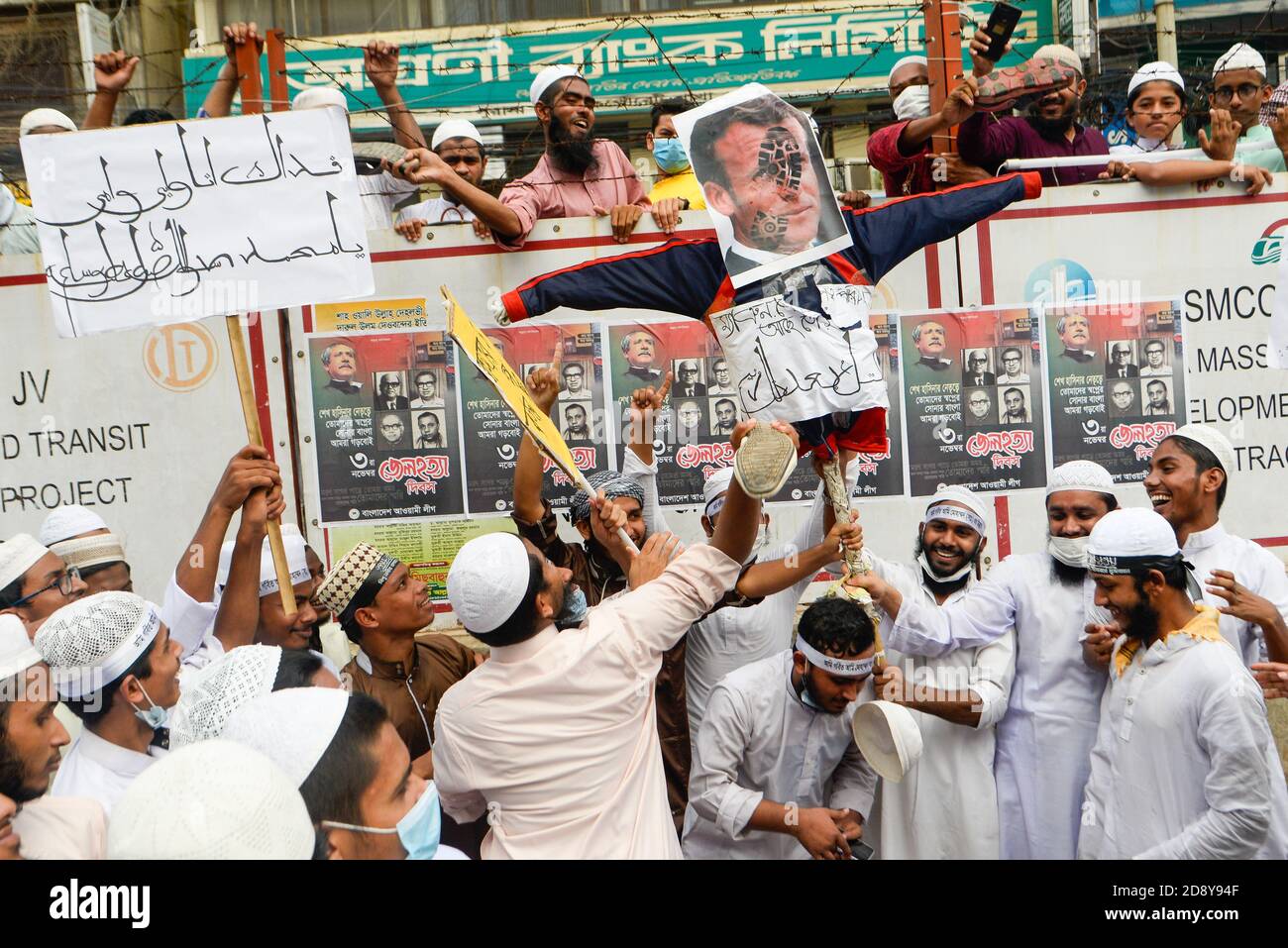 Demonstranten einer islamistischen politischen Partei halten ein Abbild des französischen Präsidenten Emmanuel Macron, während andere ihre Plakate benutzen, um ihn während des Protests in Dhaka zu treffen.Muslime protestieren zum Boykott französischer Produkte und verurteilen Präsident Emmanuel Macron für seine Kommentare über die Karikaturen des Propheten Mohammed. Stockfoto