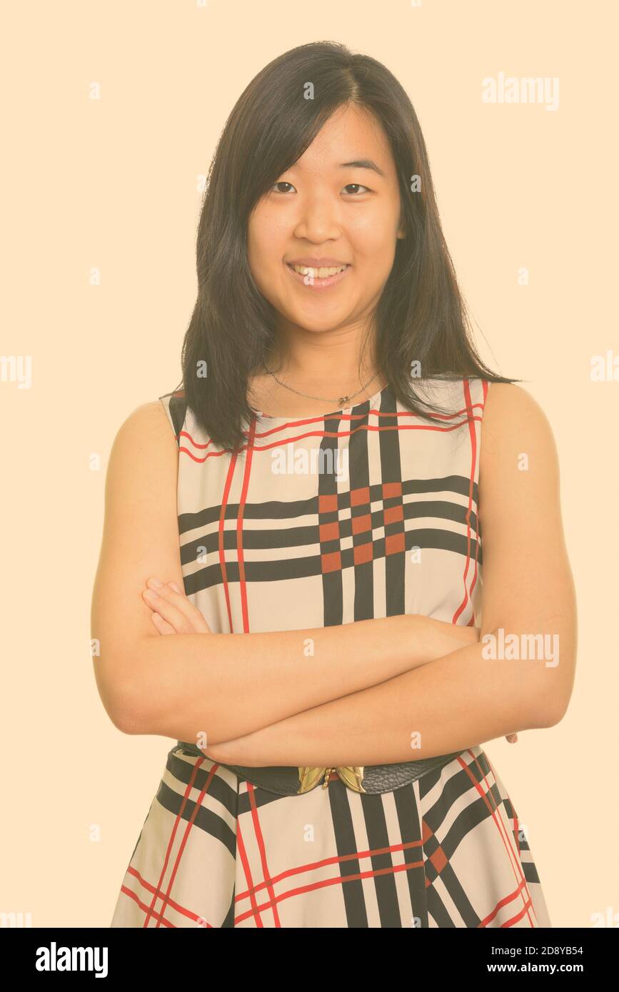Porträt der glückliche junge schöne asiatische Geschäftsfrau lächelnd mit gekreuzten Armen Stockfoto