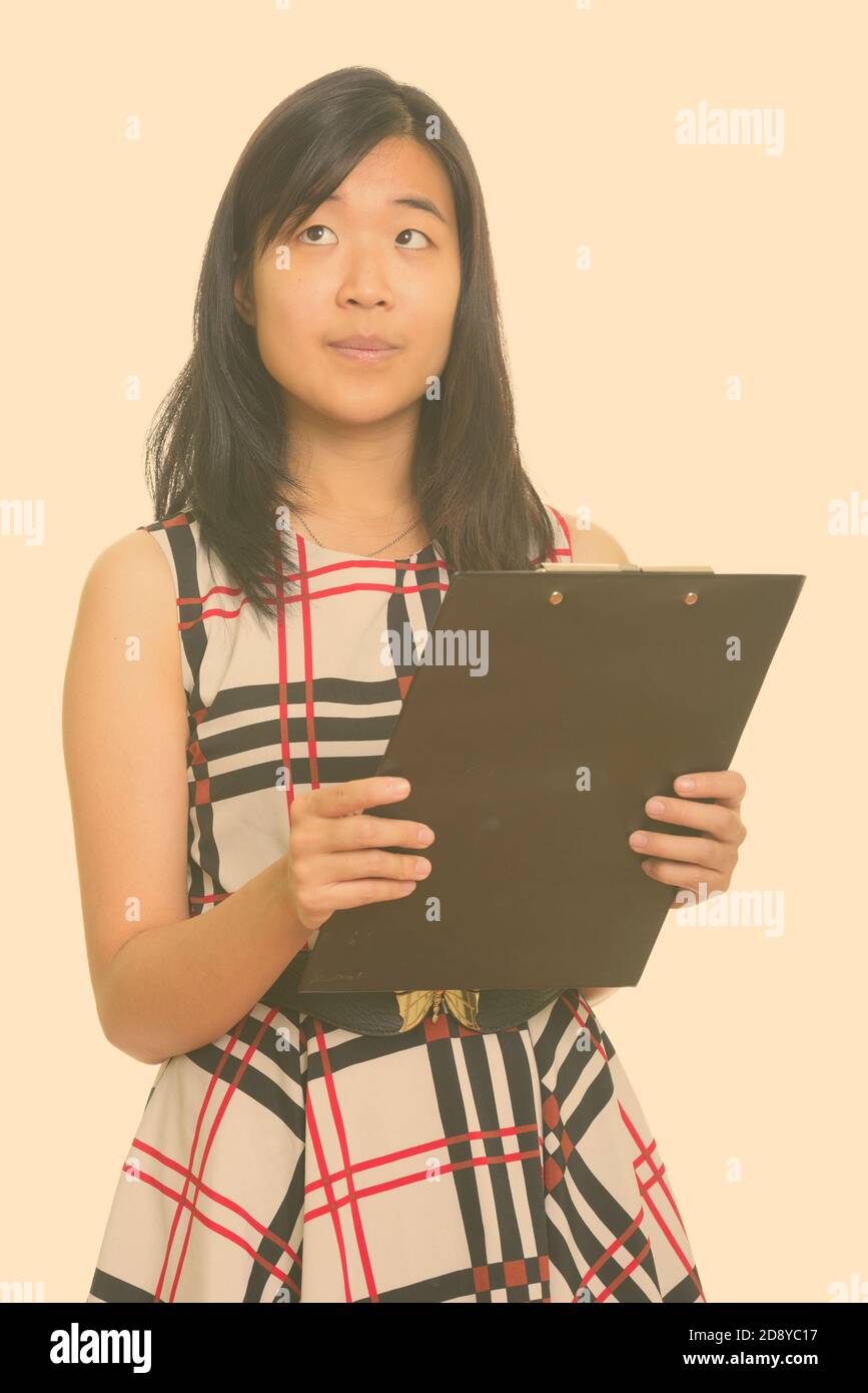 Junge schöne asiatische Geschäftsfrau holding Zwischenablage beim Denken Stockfoto