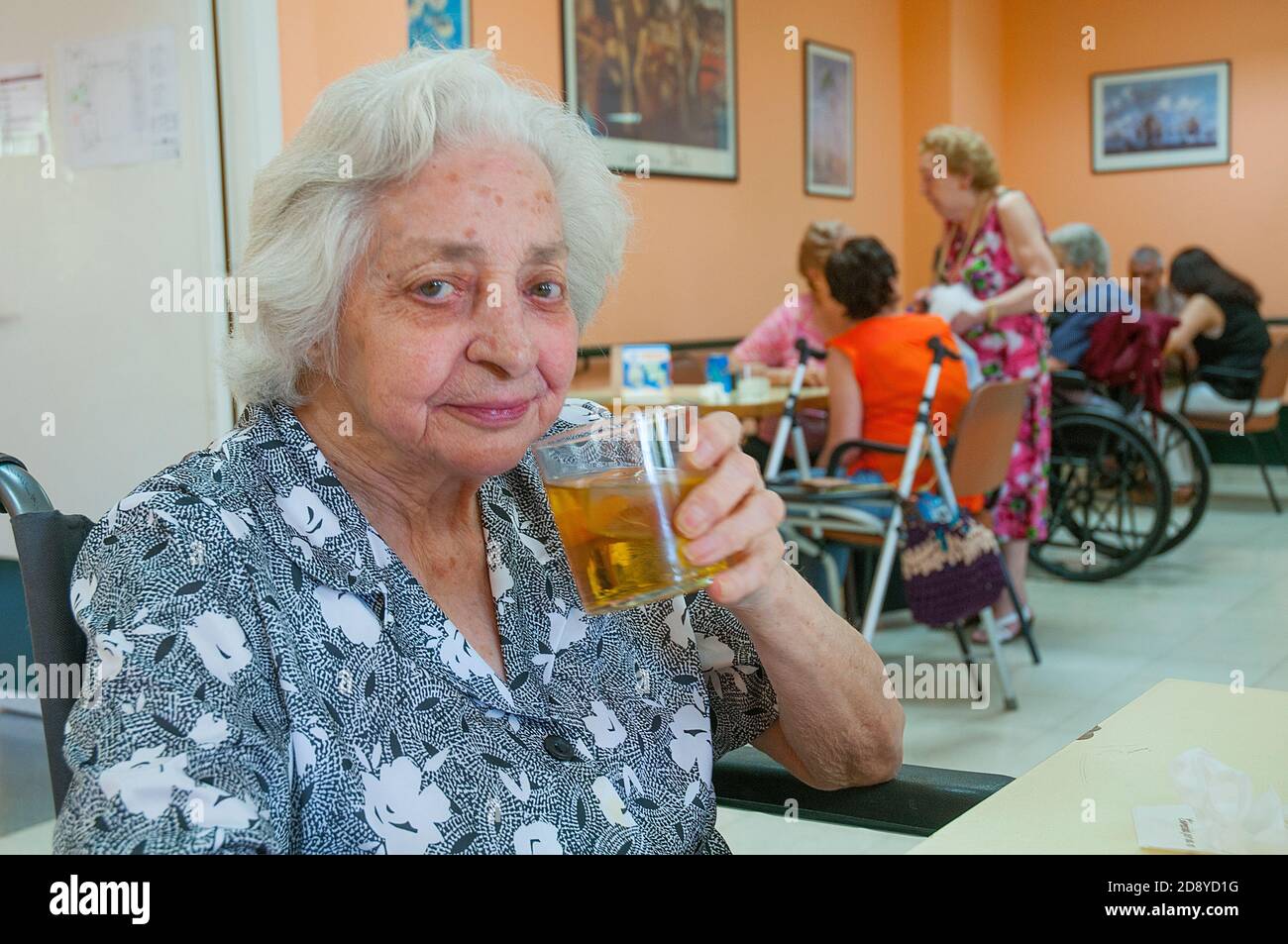 Alte Frau trinkt Traubensaft und schaut auf die Kamera. Stockfoto