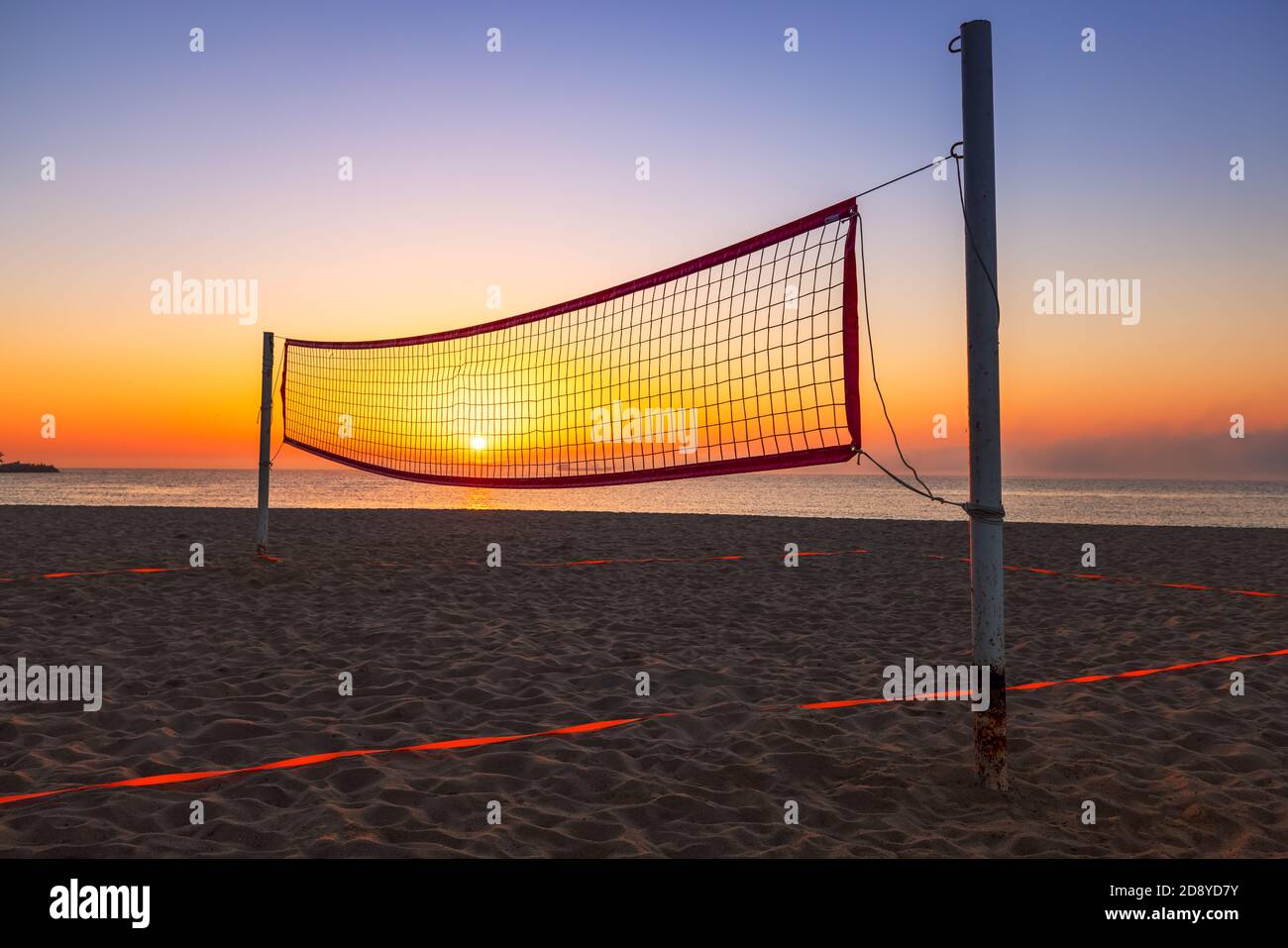 Volleyballnetz am tropischen Strand und goldener Meeresaufgang Stockfoto