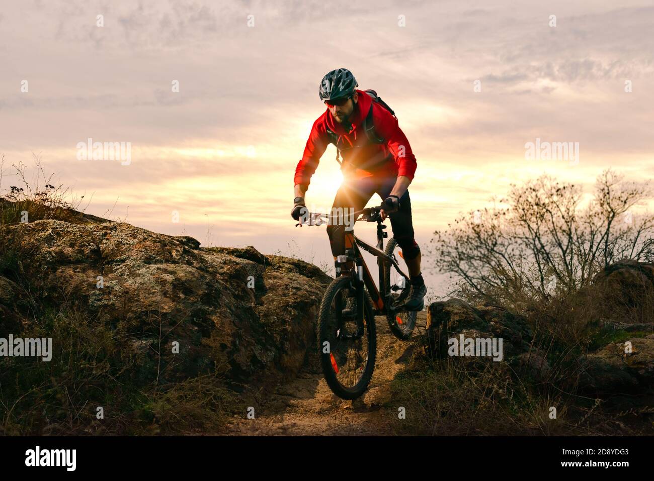 Radler in Red Riding Bike auf dem Herbst Rocky Trail bei Sonnenuntergang. Extreme Sport und Enduro Biking Konzept. Stockfoto