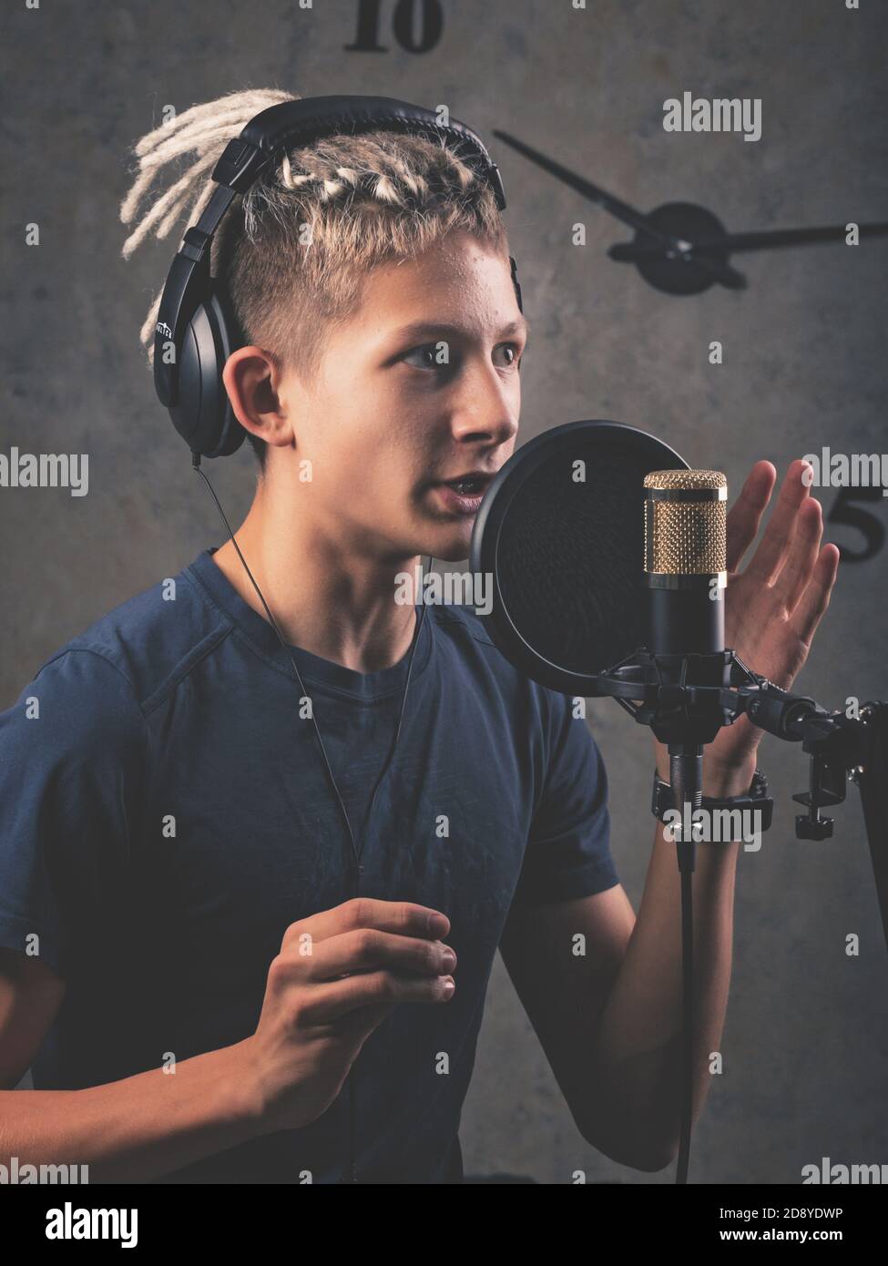 Junge Sängerin mit Dreadlocks kaukasischer Erscheinung nimmt eine Single im Studio auf. Vertikale Aufnahme Stockfoto