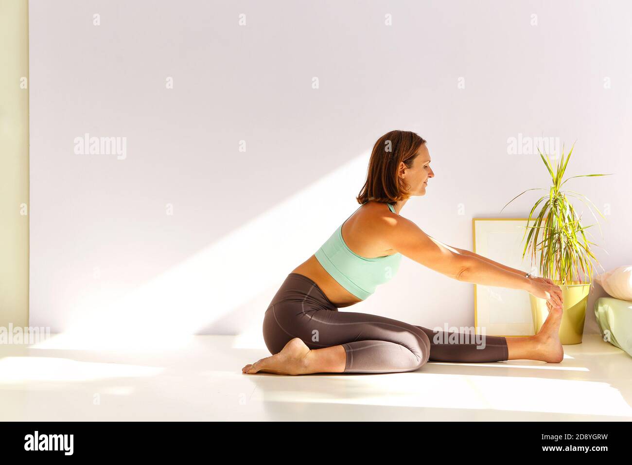 Seitenansicht einer ruhigen Frau in Sportbekleidung, in der Yoga praktiziert wird Firefly Pose beim Balancieren auf den Armen auf der Matte und suchen Weg Stockfoto