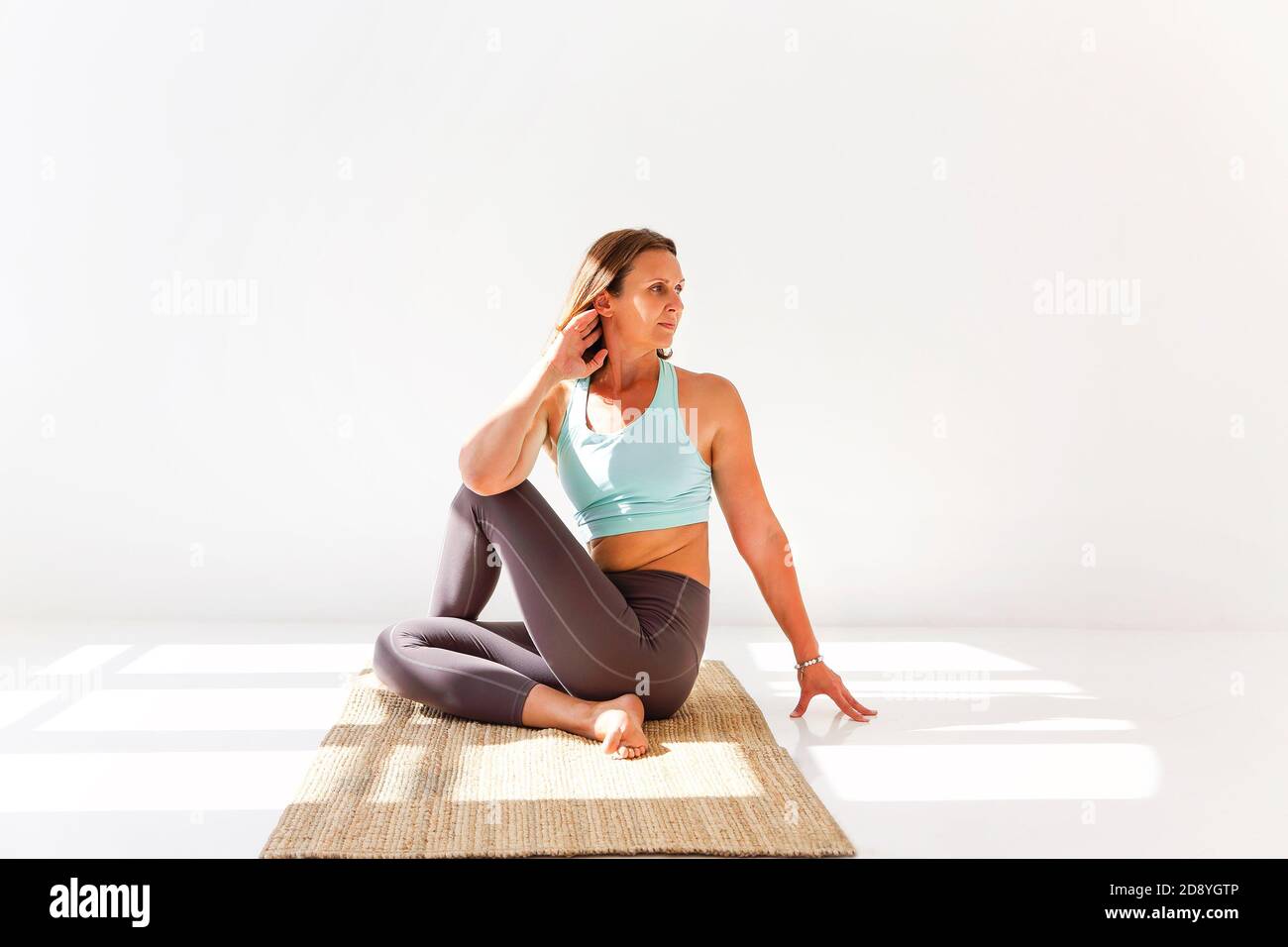 Seitenansicht einer ruhigen Frau in Sportbekleidung, in der Yoga praktiziert wird Firefly Pose beim Balancieren auf den Armen auf der Matte und suchen Weg Stockfoto