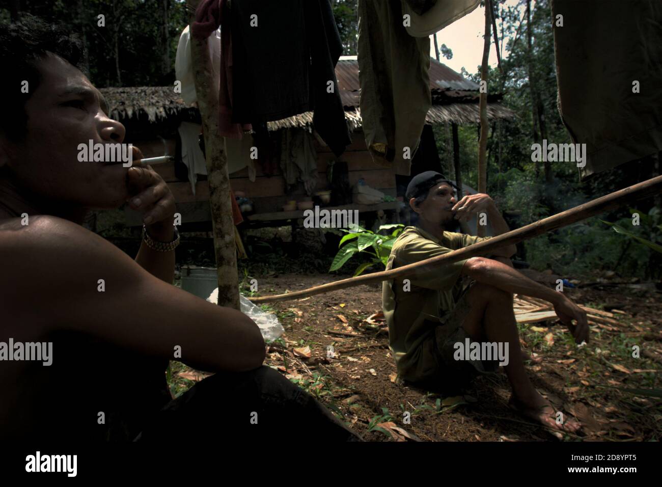 Tohab und Ramli Hutagalung, Bauern, die eine Pause auf ihrer Farm Hütte in einem Waldgebiet, das am westlichen Rand des Batang Toru Ökosystem in Sitahuis, Central Tapanuli, Nord-Sumatra, Indonesien. Gemeinden, die in und um den Regenwald leben, sind neben der Landwirtschaft zum Teil auf die Nahrungssuche und Nahrungsaufnahme angewiesen. Naturschützer haben sich diesem Thema gestellt, indem sie die Stärkung der Gemeinschaft als integralen Bestandteil jeder Naturschutzbemühung setzen, indem sie Bildung und Unterstützung für Gemeinden bei der Suche nach einer alternativen Einkommensquelle bieten, die nachhaltiger und umweltfreundlicher ist. Stockfoto