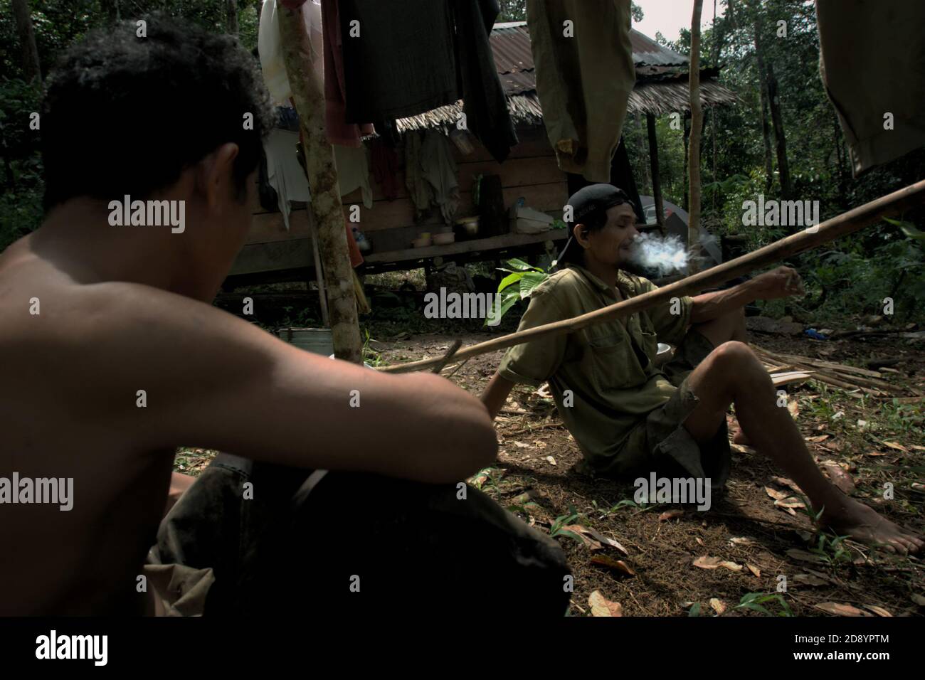 Tohab und Ramli Hutagalung, Bauern, die eine Pause auf ihrer Farm Hütte in einem Waldgebiet, das am westlichen Rand des Batang Toru Ökosystem in Sitahuis, Central Tapanuli, Nord-Sumatra, Indonesien. Gemeinden, die in und um den Regenwald leben, sind neben der Landwirtschaft zum Teil auf die Nahrungssuche und Nahrungsaufnahme angewiesen. Naturschützer haben sich diesem Thema gestellt, indem sie die Stärkung der Gemeinschaft als integralen Bestandteil jeder Naturschutzbemühung setzen, indem sie Bildung und Unterstützung für Gemeinden bei der Suche nach einer alternativen Einkommensquelle bieten, die nachhaltiger und umweltfreundlicher ist. Stockfoto
