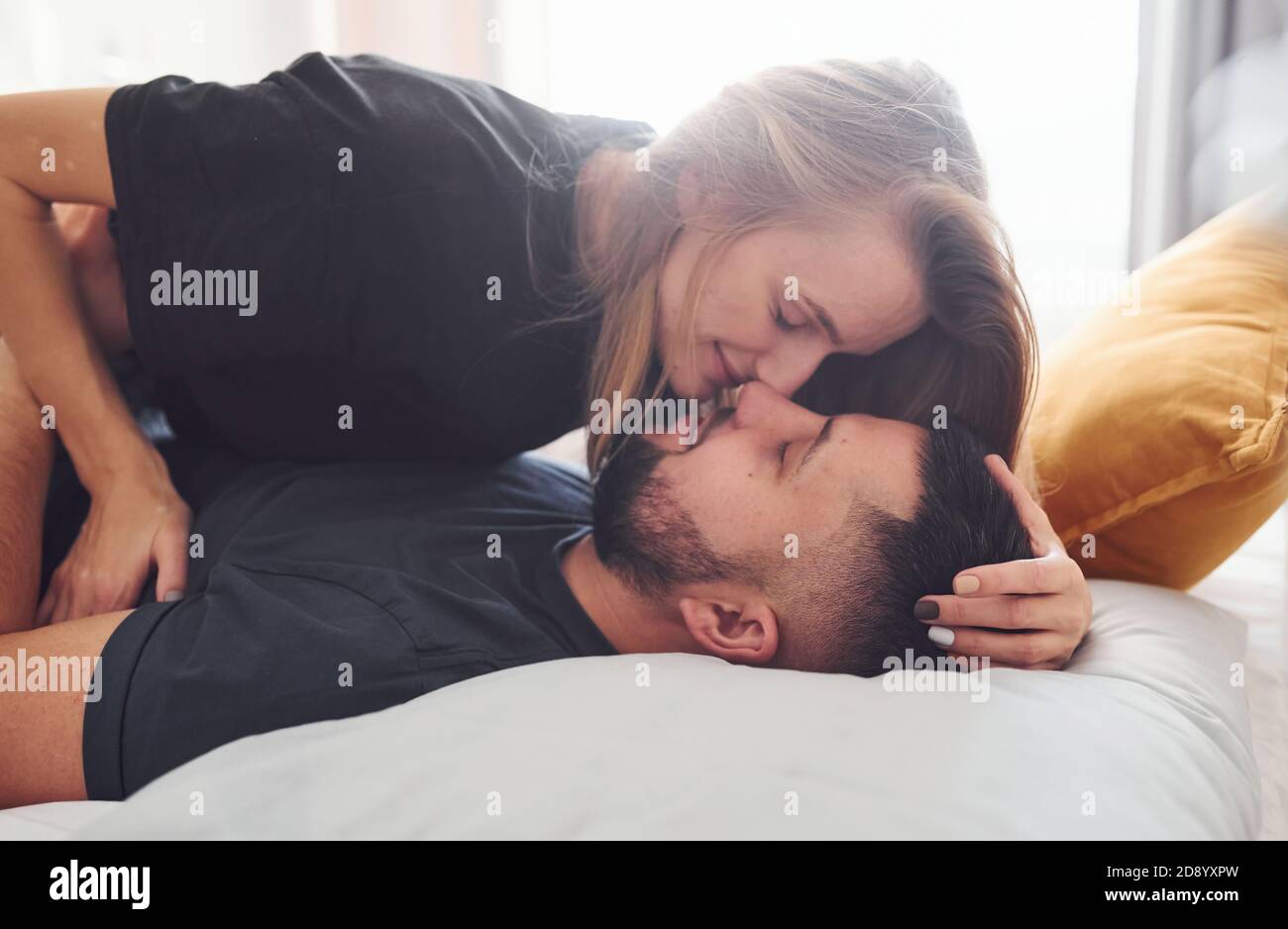 Junge verheiratete Paar küssen sich gegenseitig im Schlafzimmer am Tag  Stockfotografie