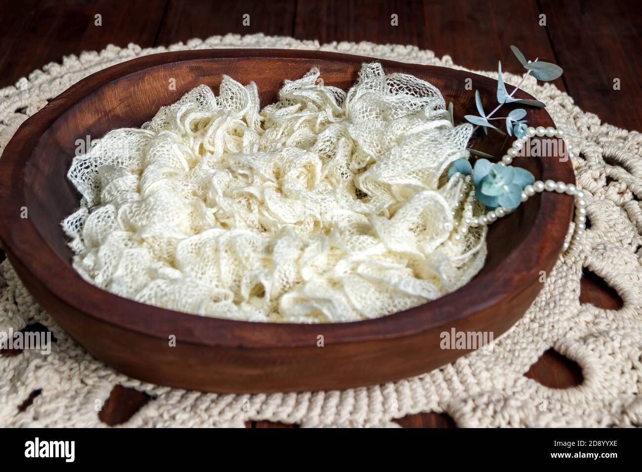 Digital Newborn Hintergrund mit einer natürlichen Holzschale auf einem Natürlicher Holzboden mit beigem Vintage-Häkel/Makrame und strukturiertem Beige Füllmaschine Stockfoto
