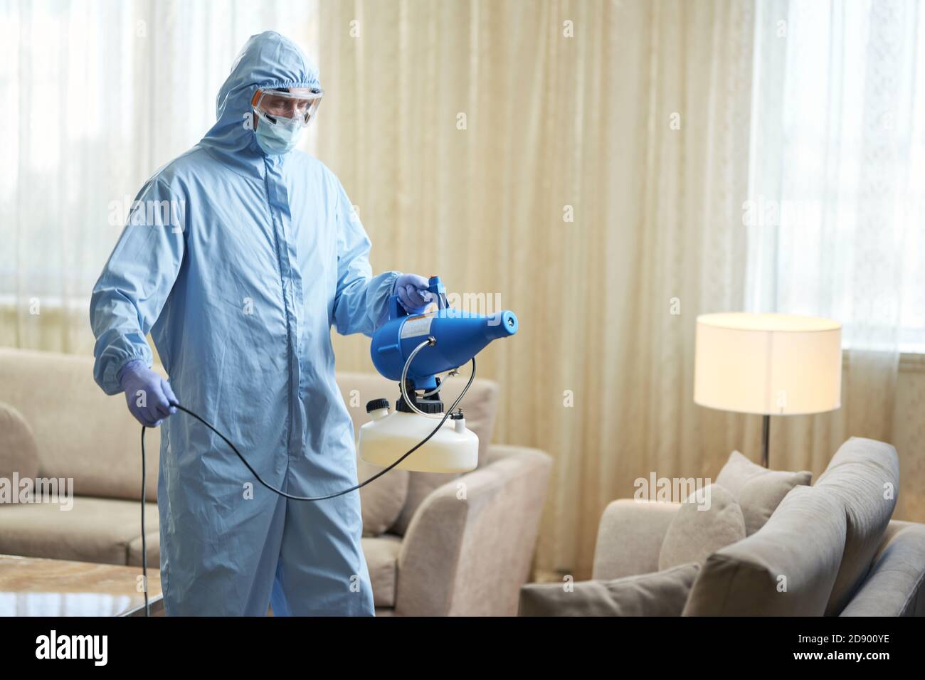Arbeiter trägt Schutzkleidung und desinfiziert eine Hotel-Wohnung Coronavirus Und Quarantänekonzept Stockfoto