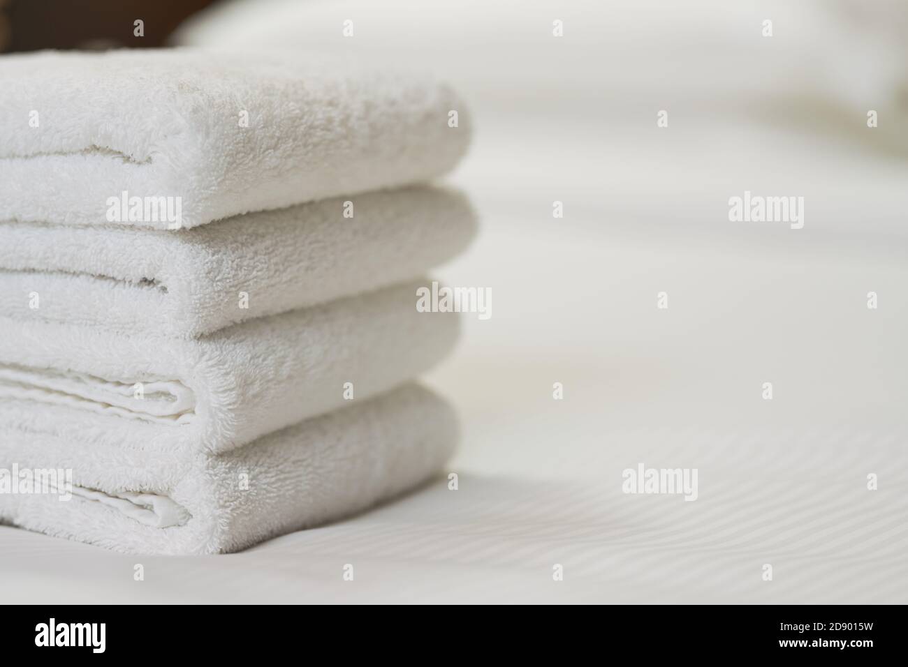 Nahaufnahme von weißen sauberen Badetüchern auf dem Bett im Hotelzimmer. Speicherplatz kopieren. Servicekonzept des Hotels Stockfoto