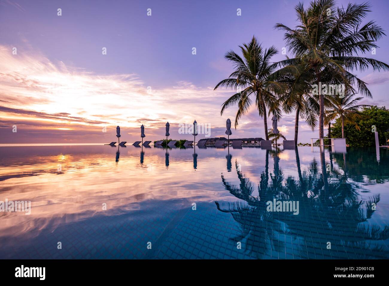 Wunderschöner Pool und Sonnenuntergang. Luxuriöse tropische Strandlandschaft, Liegestühle und Liegen und Wasserspiegelung. Erstaunlicher Sonnenuntergang Infinity Schwimmen Stockfoto