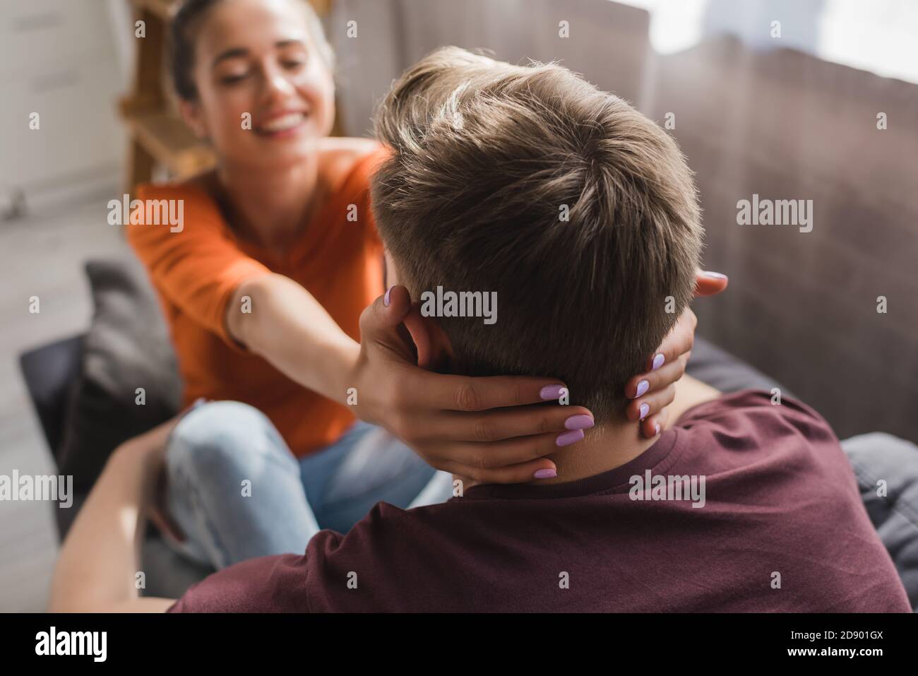 Rückansicht des Mannes nahe glückliche Frau, die seinen Hals umarmt Auf unscharfem Hintergrund Stockfoto
