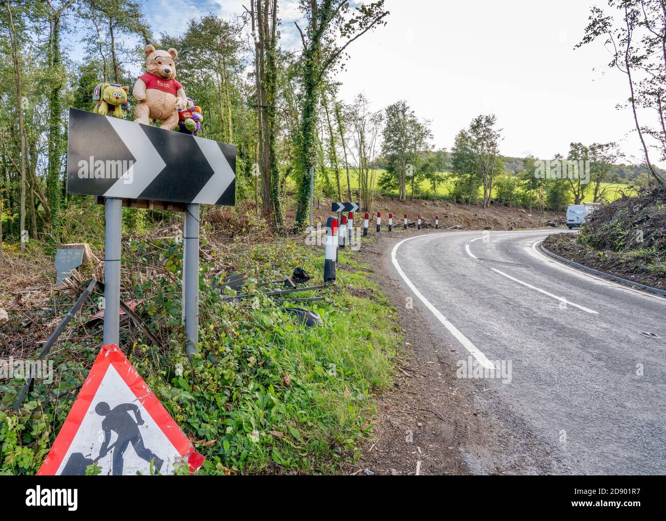 Eine Kurve in der Straße bekannt als Pooh Corner in Die Cotswold Hills von Gloucestershire UK mit Winnie the Pooh Stehen auf den Warnkeilen Stockfoto