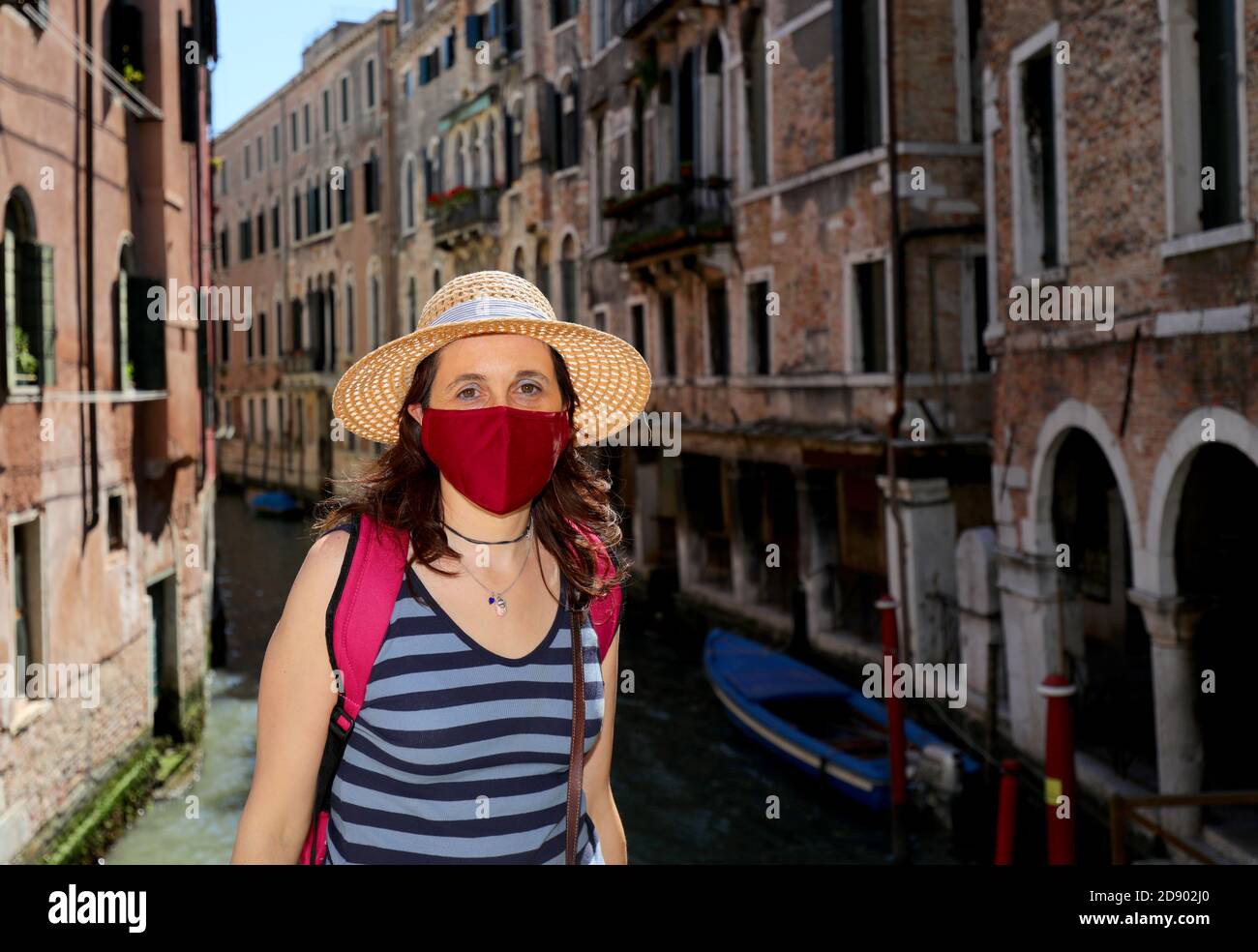 Junge Frau mit Maske und Strohhut bei einem Besuch in Venedig In ITALIEN während der Sperre Stockfoto