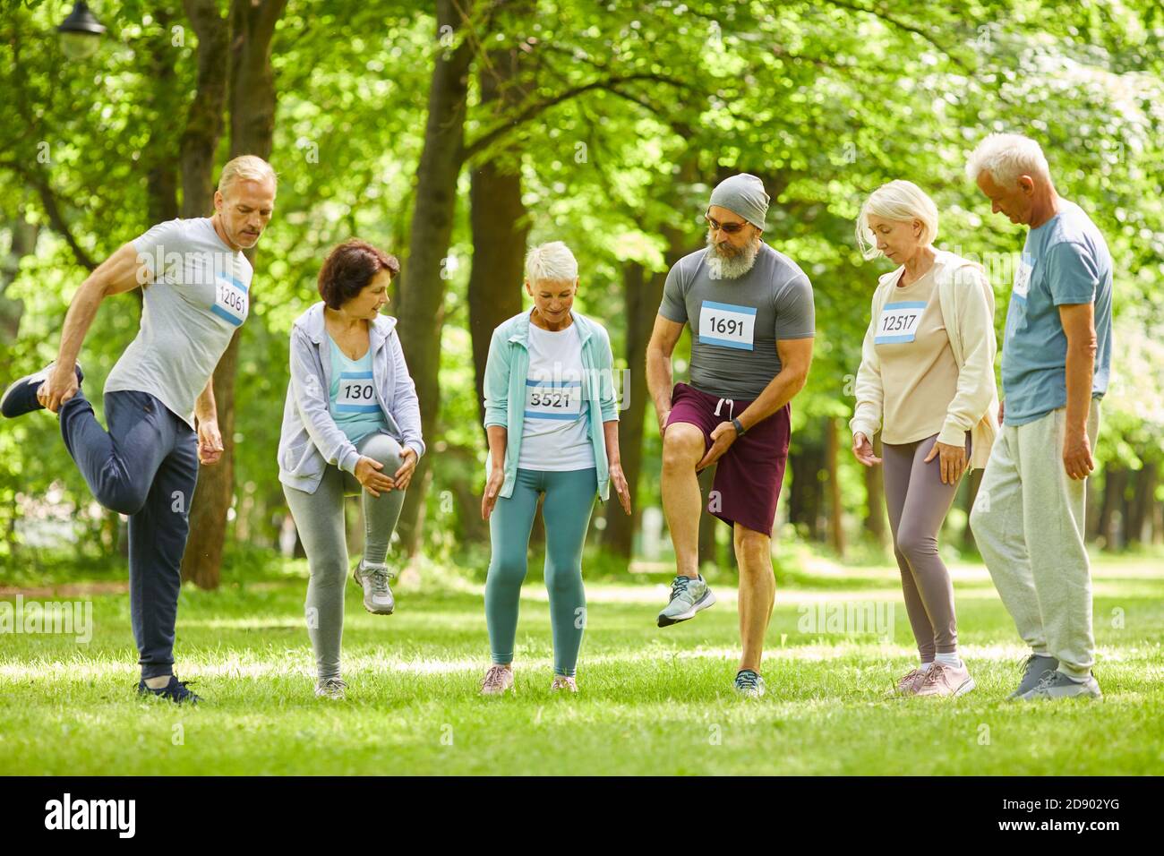 Gruppe von älteren Männern und Frauen, die am Marathon teilnehmen Training Stretching Beine kurz vor dem Laufen im Park Stockfoto