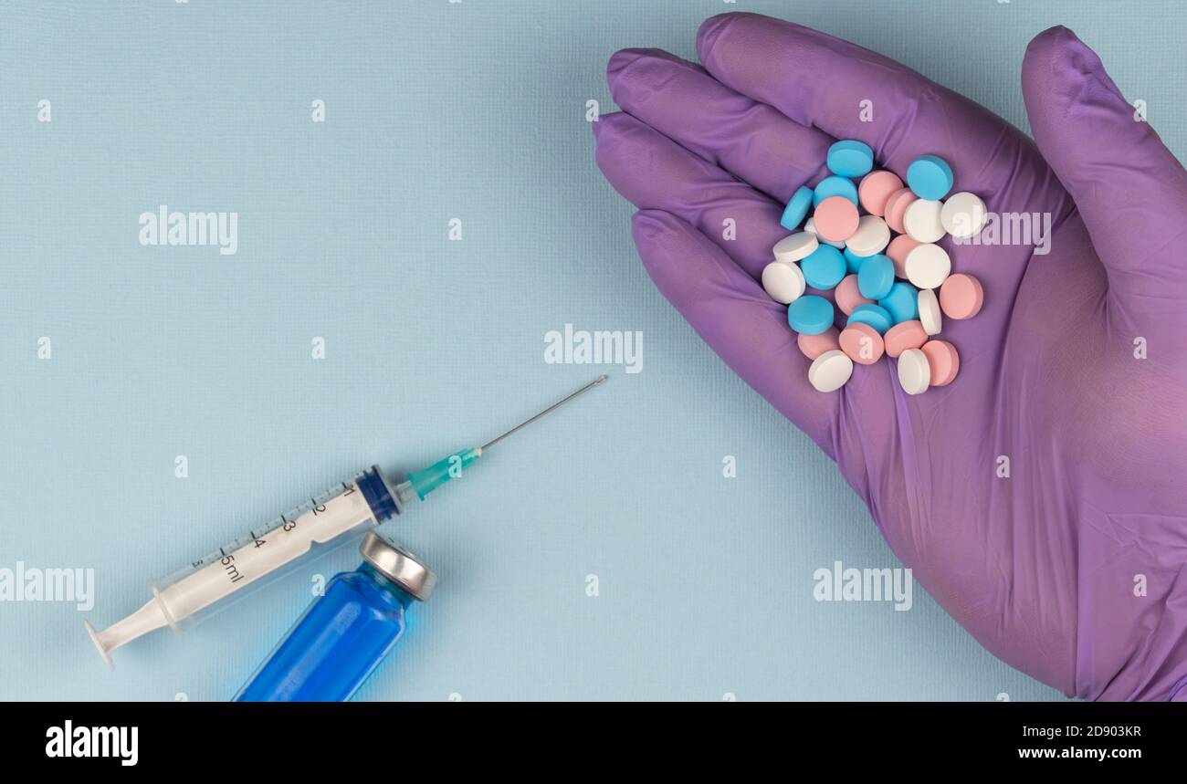 Hand in einem Gummihandschuh hält Medizin wählen zwischen Impfung und Behandlung. Stockfoto