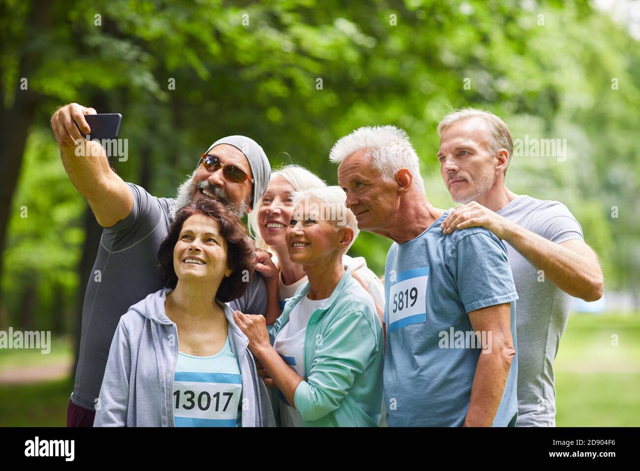 Gruppe von glücklichen älteren Freunden, die am Sommermarathon teilnehmen Rennen stehen zusammen im Waldpark machen Gruppe Selfie Foto Stockfoto