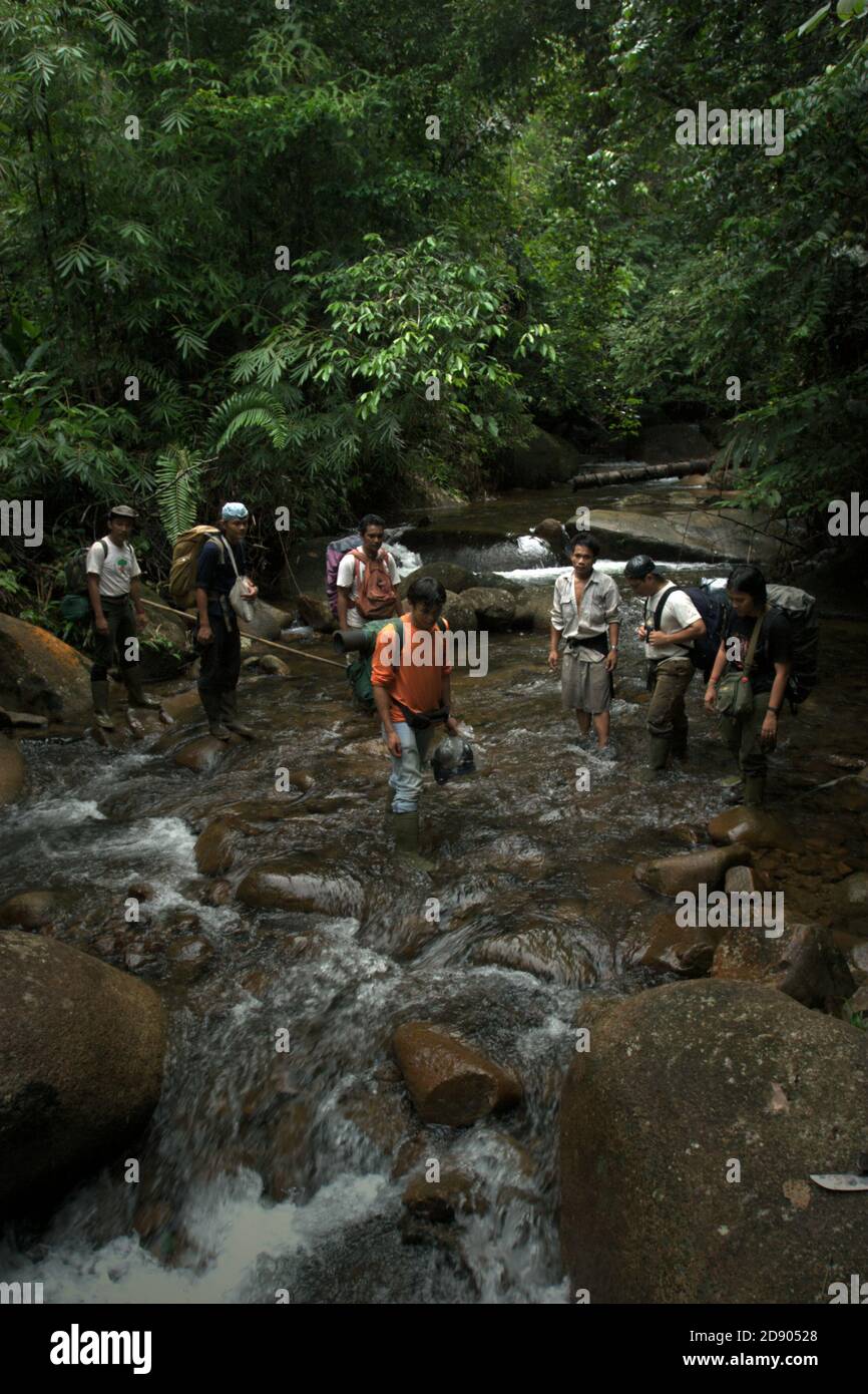 Ein Team von Schutzarbeitern, die eine Pause auf einem kleinen Fluss am westlichen Rand des westlichen Blocks des Ökosystems Batang Toru während einer Felduntersuchung in Central Tapanuli Regentschaft, Nord-Sumatra, Indonesien. Stockfoto
