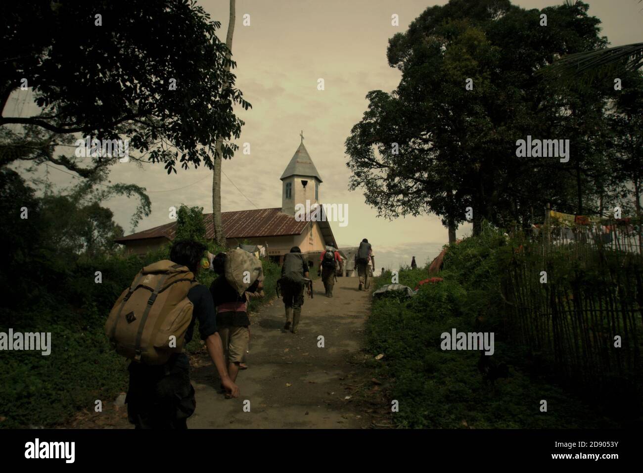 Eine Gruppe von Schutzarbeitern, die auf der Landstraße des Dorfes Nauli spazieren, nachdem sie eine Felduntersuchung am westlichen Rand des Ökosystems Batang Toru im Sitahuis-Bezirk, Central Tapanuli, Nord-Sumatra, Indonesien, durchgeführt haben. Stockfoto