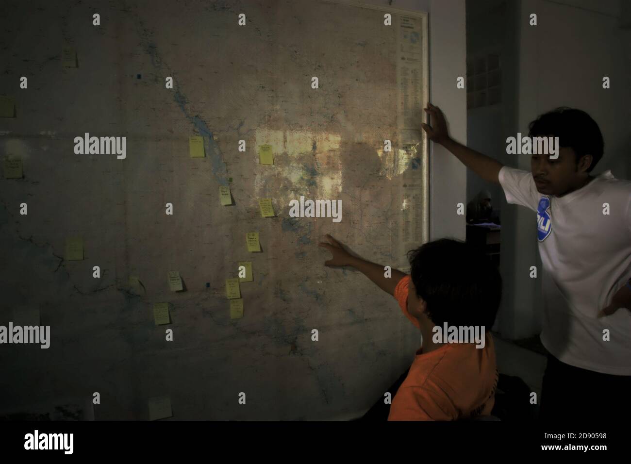 Conservation Workers diskutieren die Umfrageorte auf einer topografischen Karte von Batang Toru Wasserscheide und Regenwald an einer Wand im Außenbüro von Conservation International in Sibolga, Nord-Sumatra, Indonesien. Stockfoto
