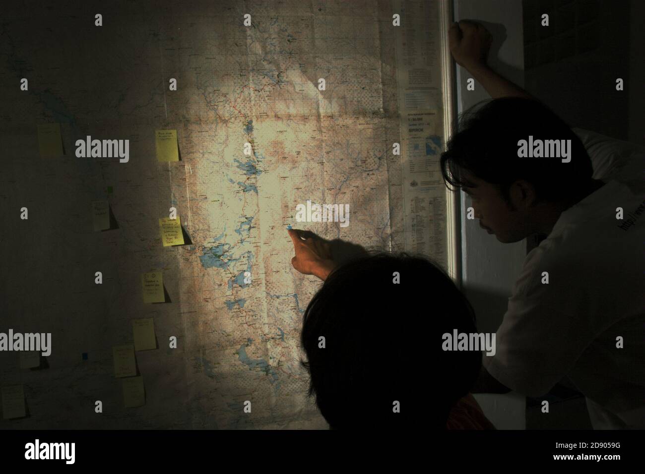 Conservation Workers diskutieren die Umfrageorte auf einer topografischen Karte von Batang Toru Wasserscheide und Regenwald an einer Wand im Außenbüro von Conservation International in Sibolga, Nord-Sumatra, Indonesien. Stockfoto