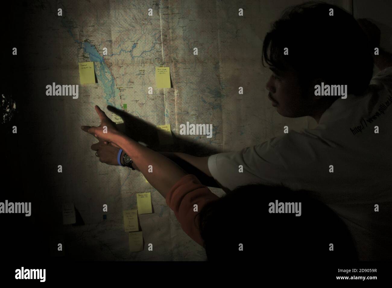 Conservation Workers diskutieren die Umfrageorte auf einer topografischen Karte von Batang Toru Wasserscheide und Regenwald an einer Wand im Außenbüro von Conservation International in Sibolga, Nord-Sumatra, Indonesien. Stockfoto