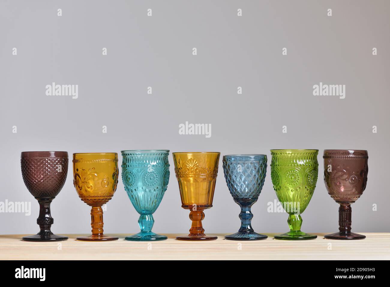 Set von leeren Gläsern aus farbigem Glas auf grau Hintergrund Stockfoto