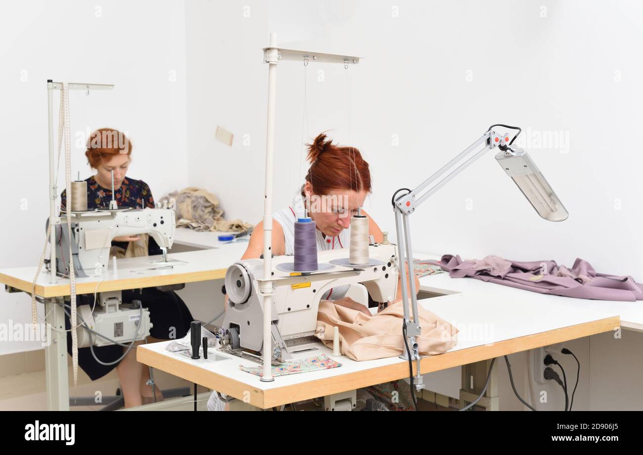 Zwei kaukasische Frauen Näherin bei der Arbeit an Nähmaschinen in Ein Nähstudio Stockfoto