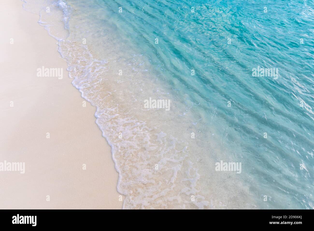 Sanfte Welle des blauen Ozeans am Sandstrand. Entspannender Meeresküste Hintergrund. Sanfte, sanfte Wellen, die auf weißem Sand planschen, tropische Strandküsten Stockfoto