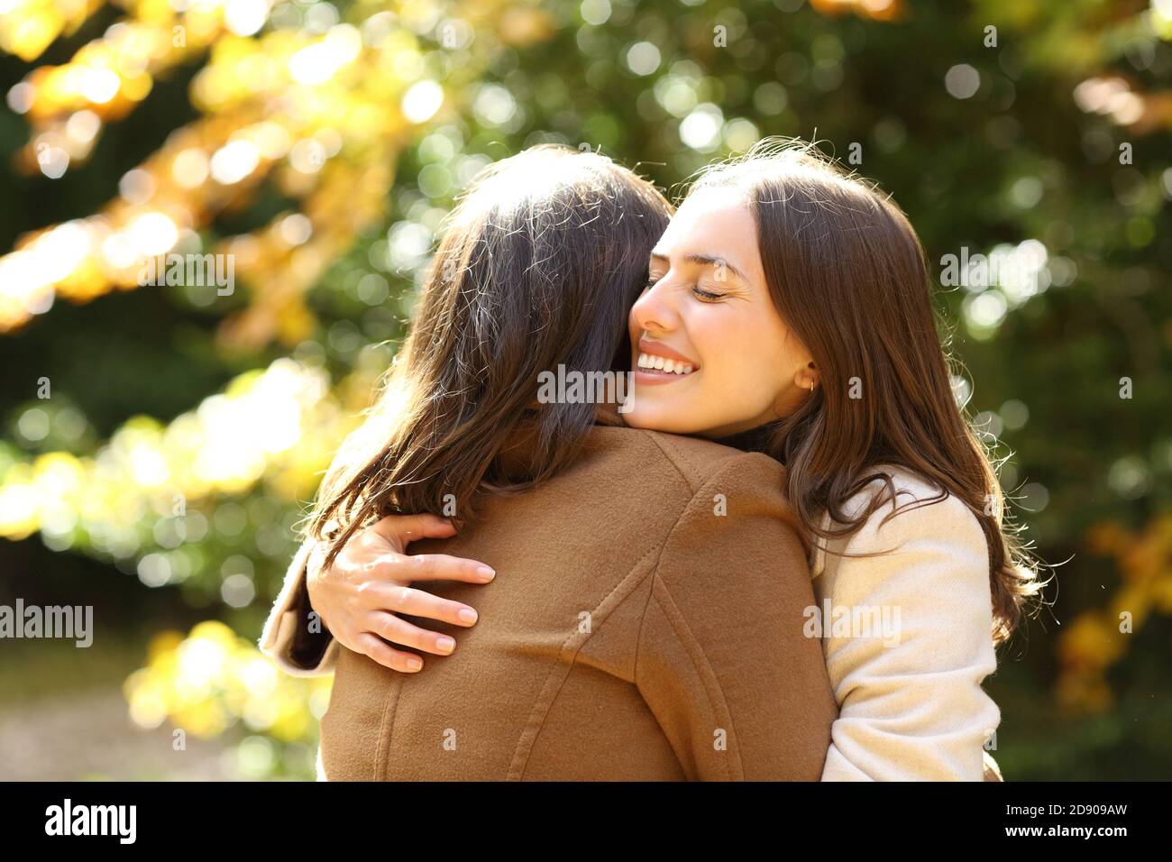 Glückliche Freunde treffen und umarmen in einem Park im Herbst Jahreszeit einen sonnigen Tag Stockfoto