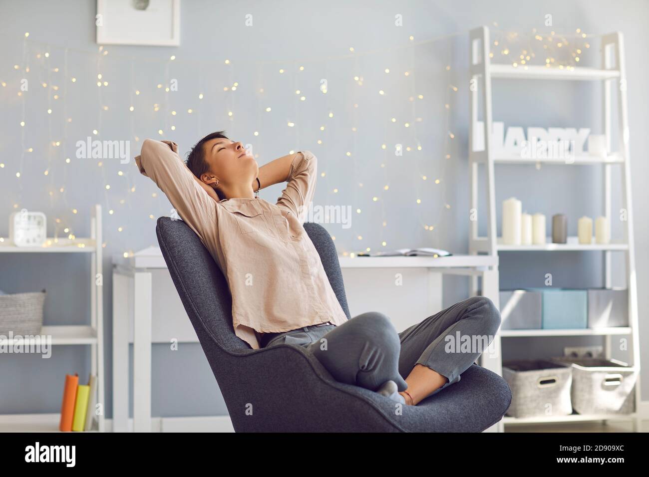 Entspannte junge Frau lehnte sich zurück in Sessel im Home Office Glücklich, dass die Arbeit erledigt ist Stockfoto