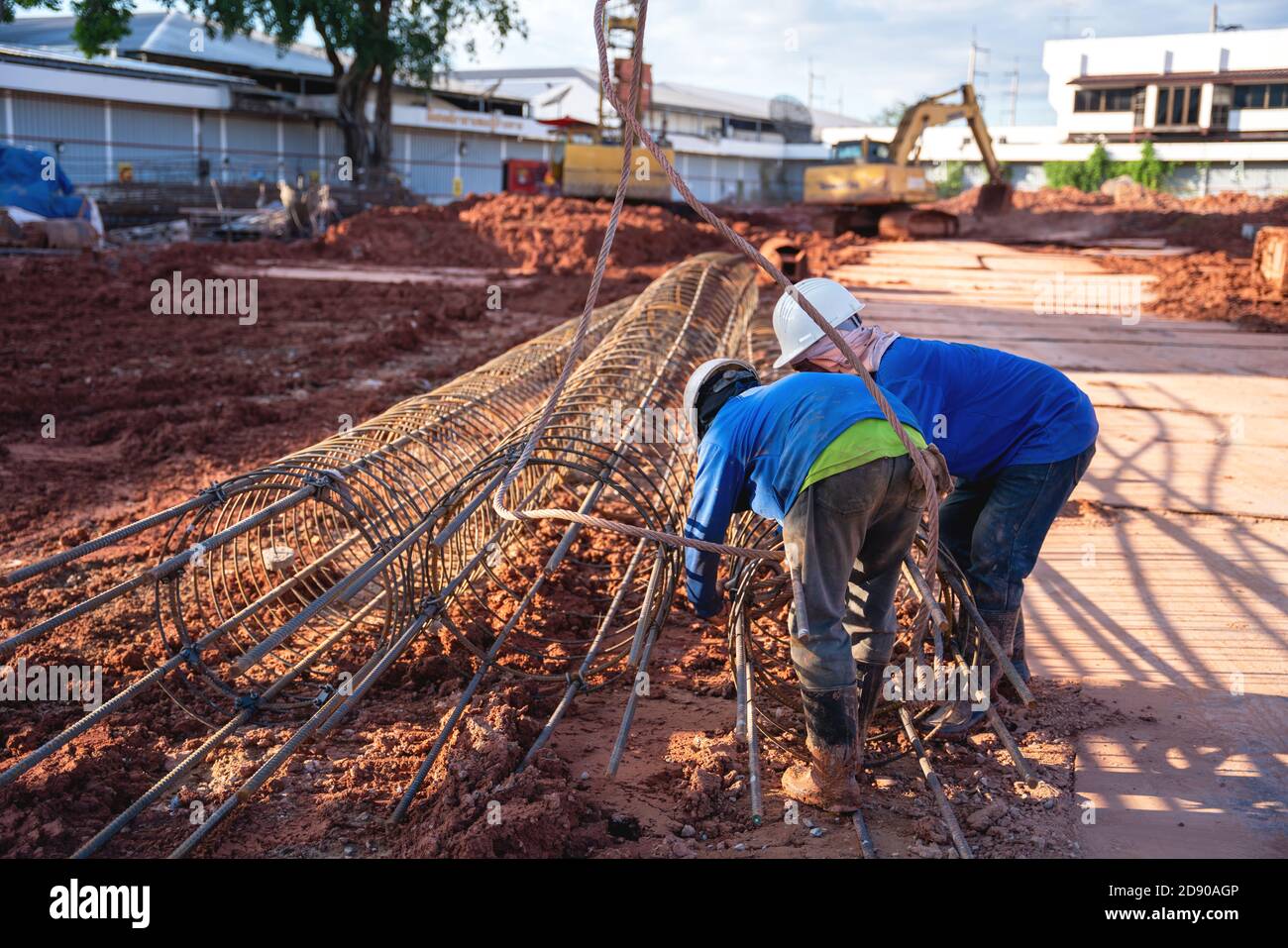 Bauarbeiter installieren eine Hebeschlinge, die Stahlgewebe zu Die Last, während der Kran die Baustelle hebt Stockfoto