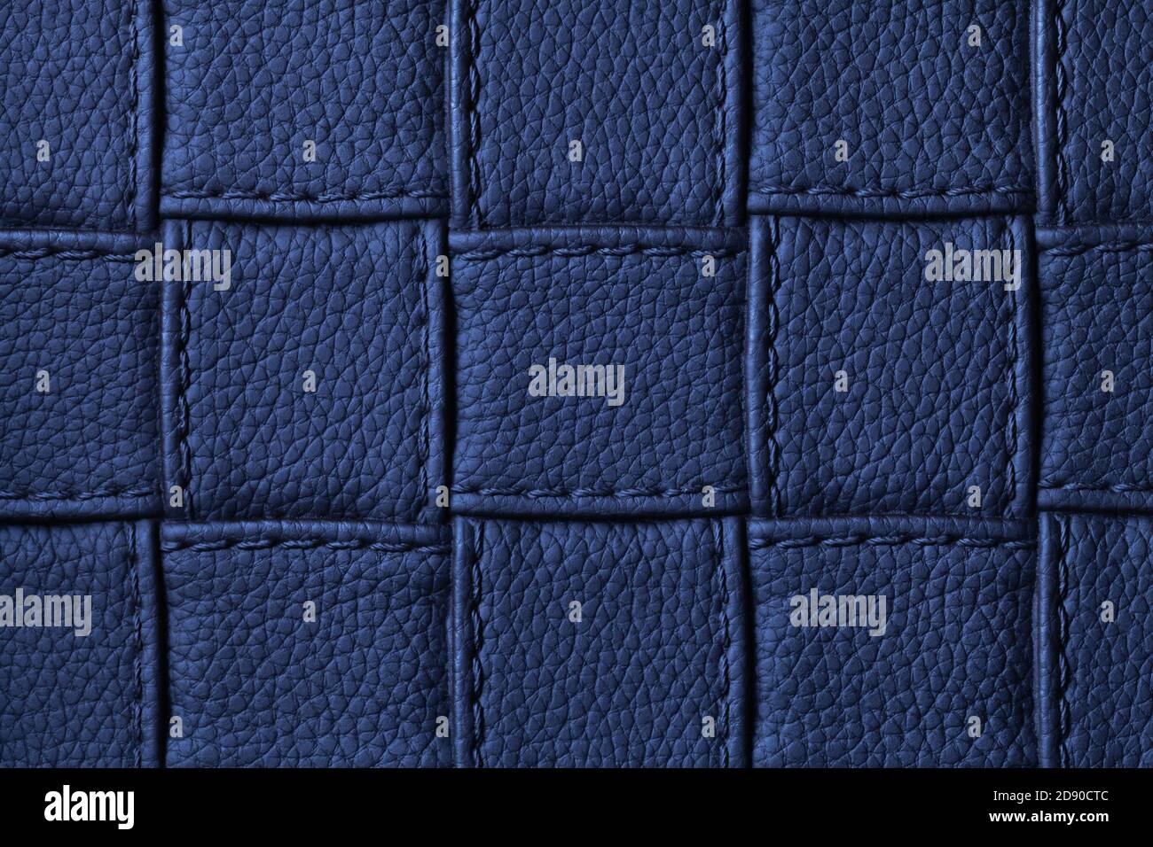 Textur von marineblauem Leder Hintergrund mit quadratischen Muster und Stich, Makro. Abstrakte Kulisse aus modernem dekorativem dunklem Indigo-Textil mit geome Stockfoto