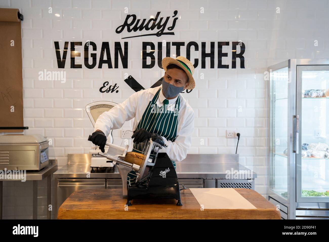 Rudys Vegan Butcher Delikatessengeschäft wird in Islington London eröffnet. Bild zeigt 'Metzger', der Fleischersatz aufschlitzt, Gesichtsmaske trägt. Stockfoto