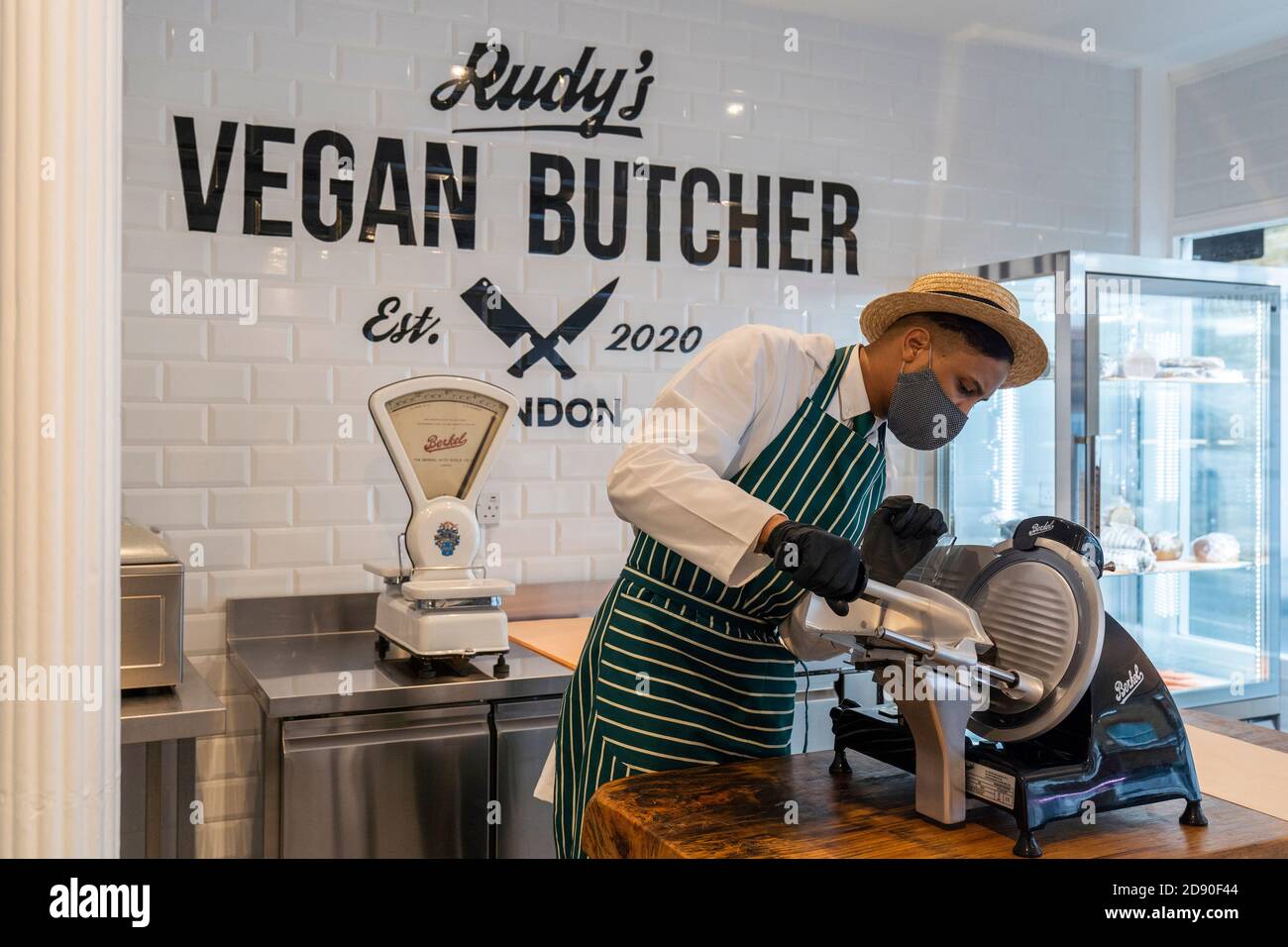 Rudys Vegan Butcher Delikatessengeschäft wird in Islington London eröffnet. Bild zeigt 'Metzger', der Fleischersatz aufschlitzt, Gesichtsmaske trägt. Stockfoto