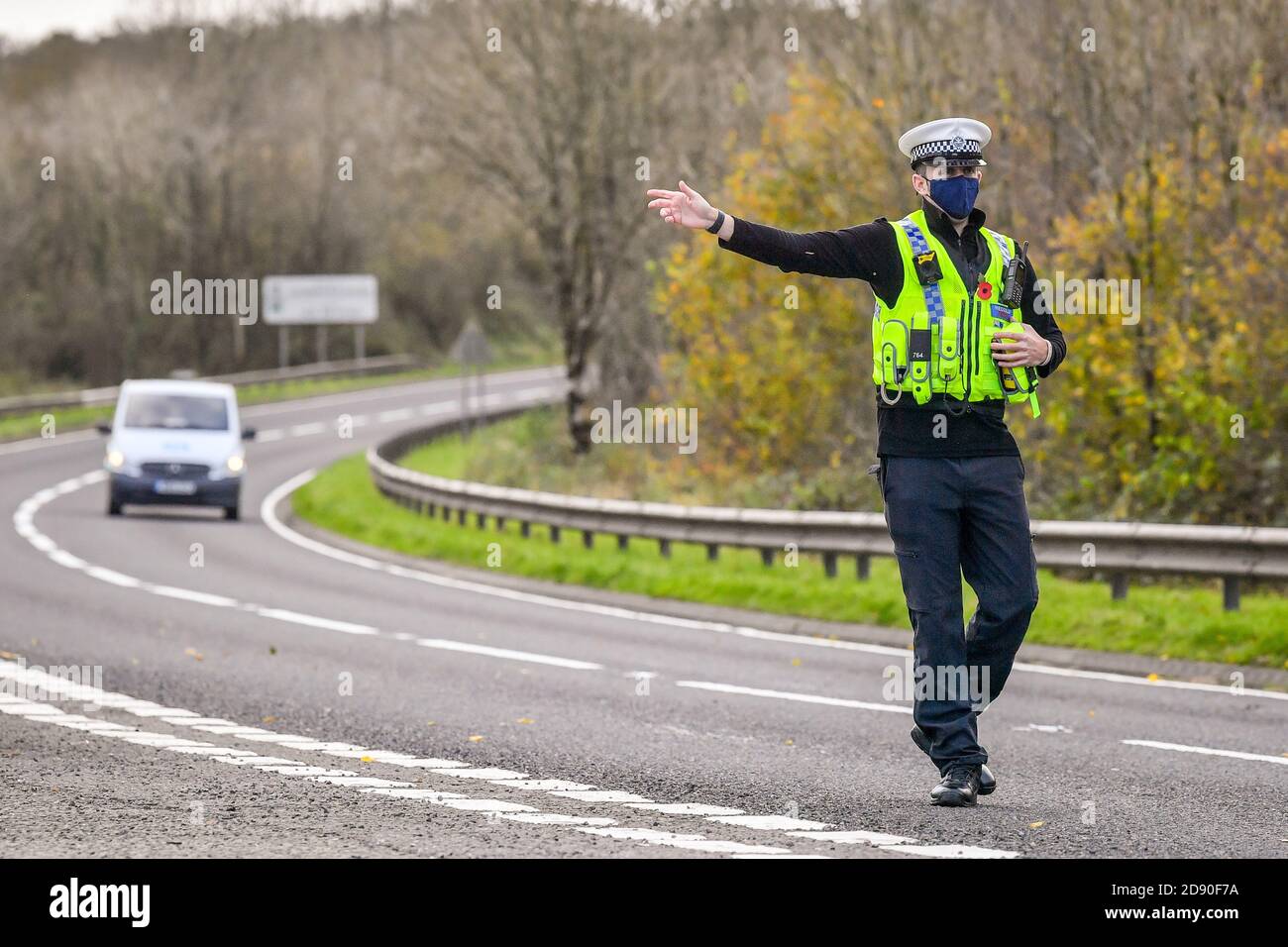 Walisische Polizei zieht Autos an einem Kontrollpunkt während Feuerbremsfahrzeuge Patrouillen nahe der Grenze zwischen Camarthenshire und Pembrokeshire, Wales. Erster Minister Mark Drakeford wird am Montag neue nationale Coronavirus-Maßnahmen für Wales vorstellen. Stockfoto