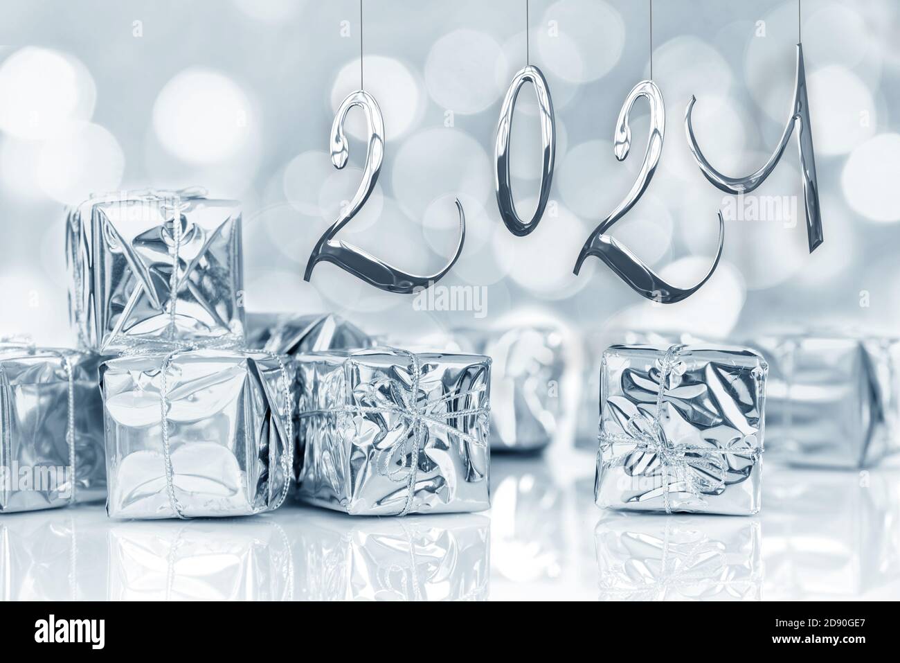 2021, Jahreskarte, kleine Weihnachtsgeschenke in glänzendem Silberpapier, Bokeh Lichter Hintergrund Stockfoto