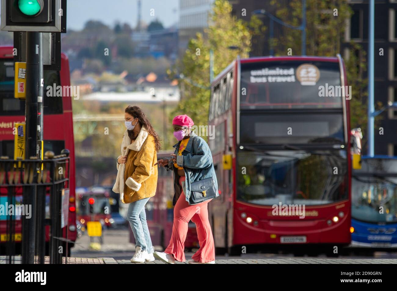 Zwei Frauen in farbenfrohen Outfits und Gesichtsmasken in Birmingham Das Stadtzentrum als eine weitere nationale Sperre steht für Großbritannien an Stockfoto