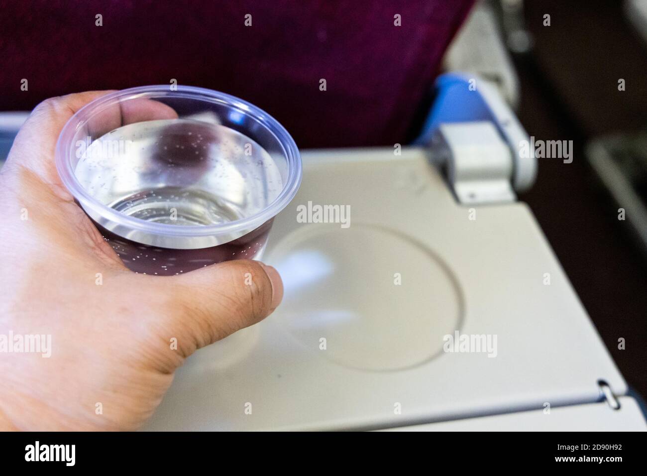 Hand hält Glas Wasser auf dem Tisch. Trinken Sie, um Austrocknung zu verhindern. Stockfoto